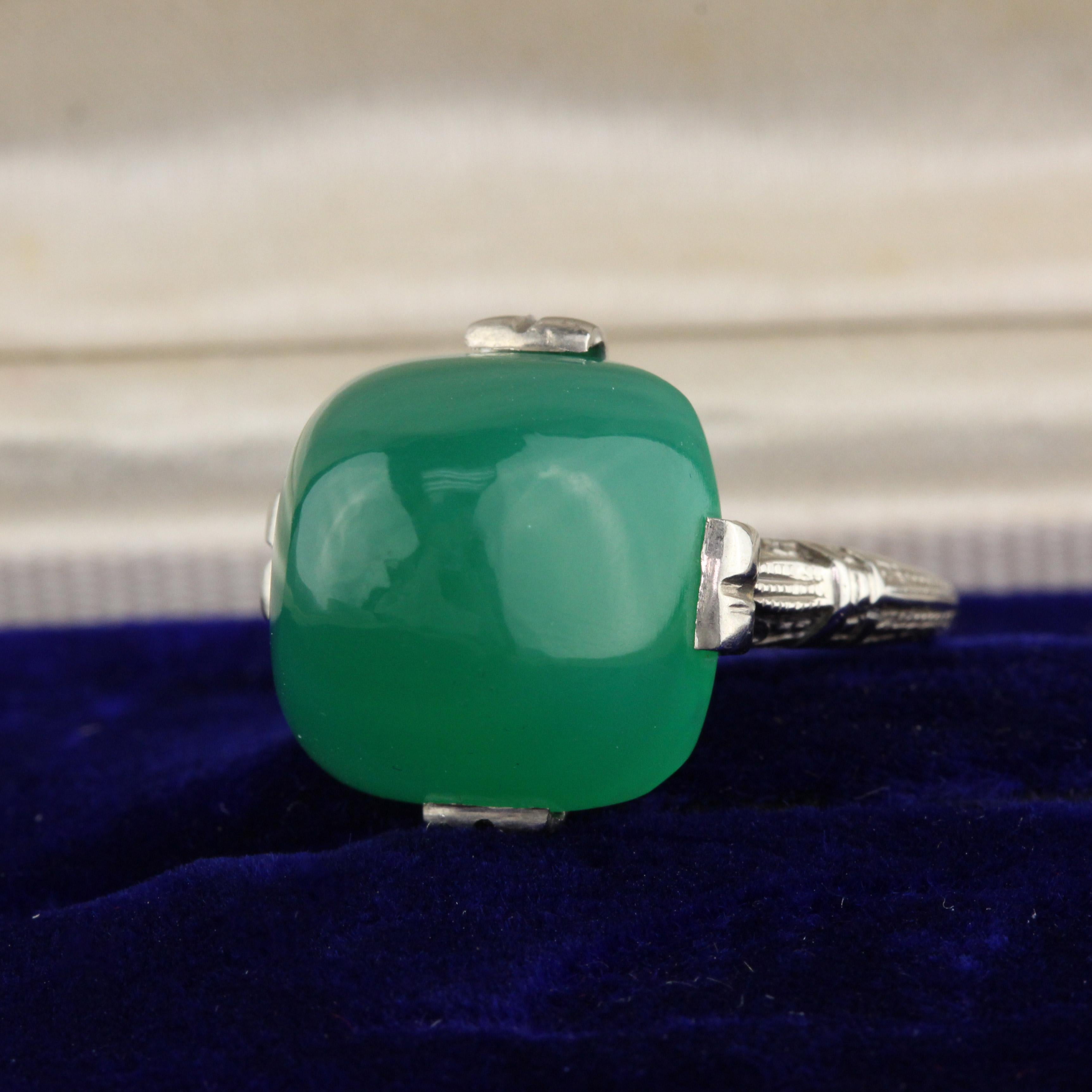 Beautiful Art Deco Engraved Mounting showcases a green cabochon chrysoprase in this antique ring.

#R0011

Metal: 14K White Gold

Weight: 4.4 grams

Ring Size: 3 1/4

This ring can be sized for a $30 fee!

*Please note that we cannot accept returns