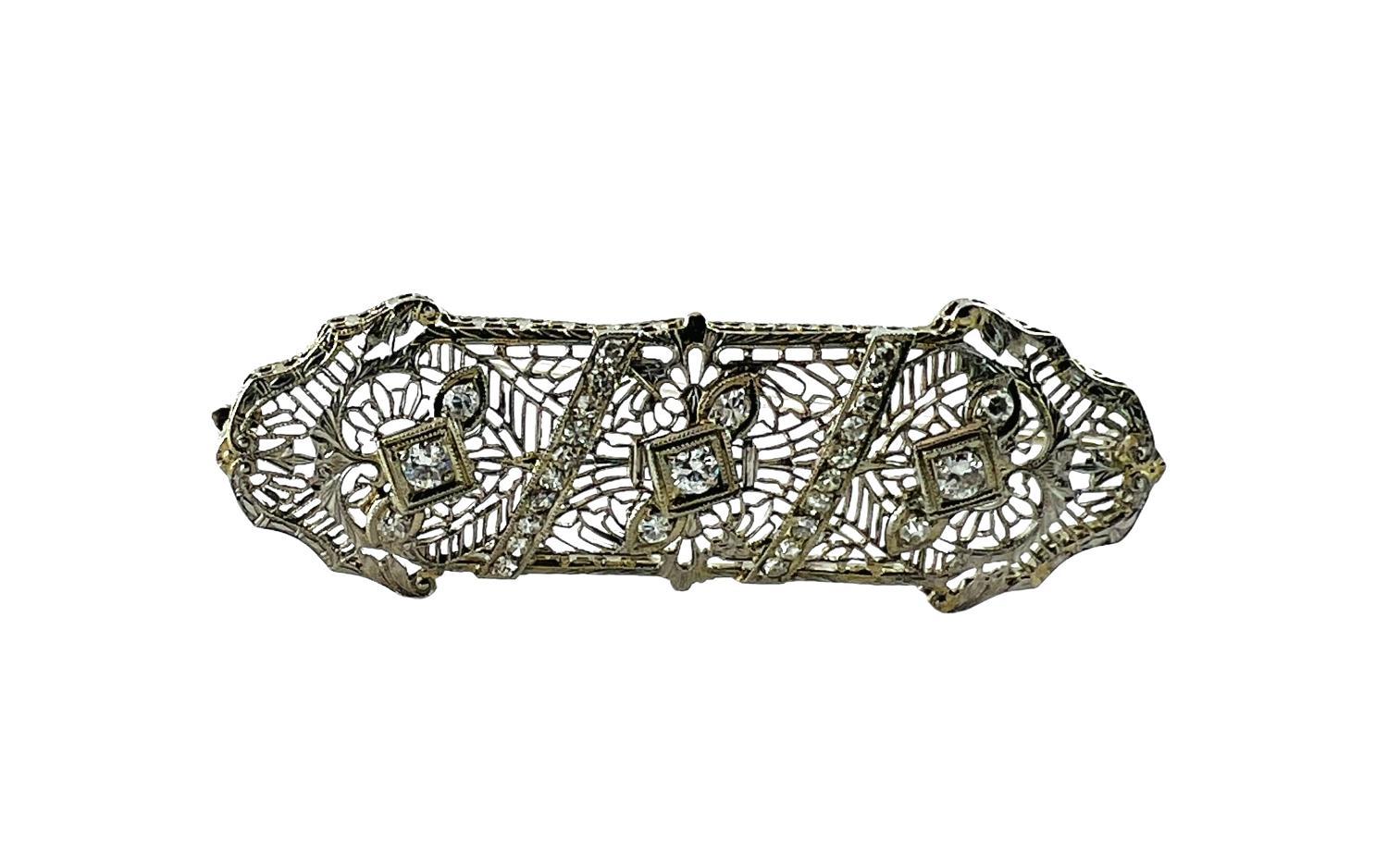 Beautiful14K white gold long antique Art Deco lacy filigree diamond brooch pin.

Circa 1920-1930

3 single diamonds representing flowers with diamond leaves on either side are spaced apart by 2 bars of sparkling diamonds.

Brooch measures: 2 13/16