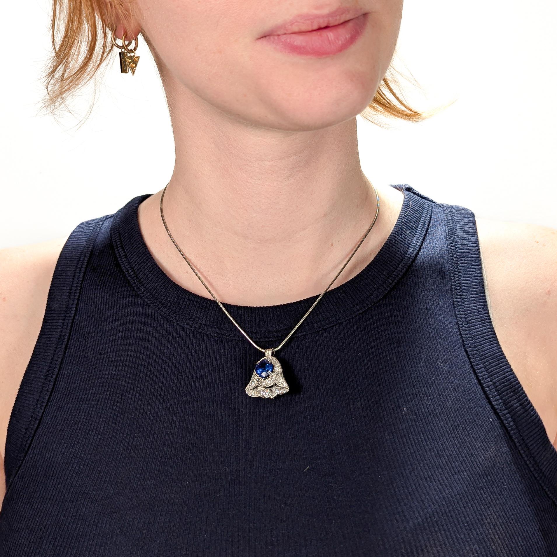 A fine antique Art Deco gold, tanzanite, & diamond convertible pendant / brooch.

In 14 karat white gold.

In the form of a bell or inverted tulip flower. 

Set with a central prong-set 4.03± ct round modified brilliant cut tanzanite (transparency: