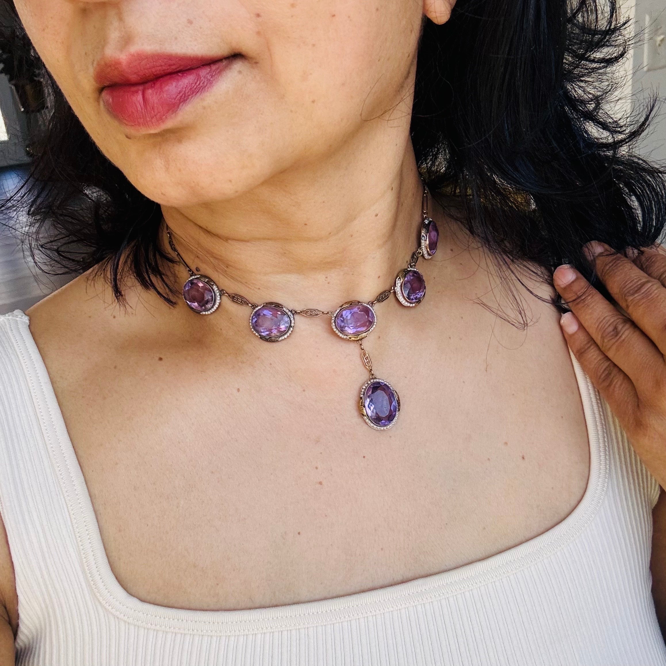 This exquisite Art Deco necklace is a stunning example of early 20th-century craftsmanship, set in 14kt gold. The piece features six natural amethyst stones, each set in an open-back setting that allows light to enhance their rich purple hue. Each