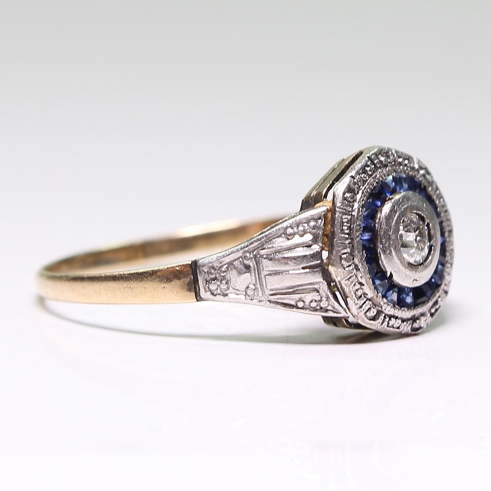 Period: Art Deco (1920-1935)
Composition: 18K gold and Platinum

Stones:
•	1 Old mine cut diamond of H-VS2 quality that weighs 0.08ctw. 
•	20 natural calibrated cut sapphires that weigh 0.70ctw. 
Ring size: 8 ½ 
Ring face:  17mm by 10mm 
Rise above