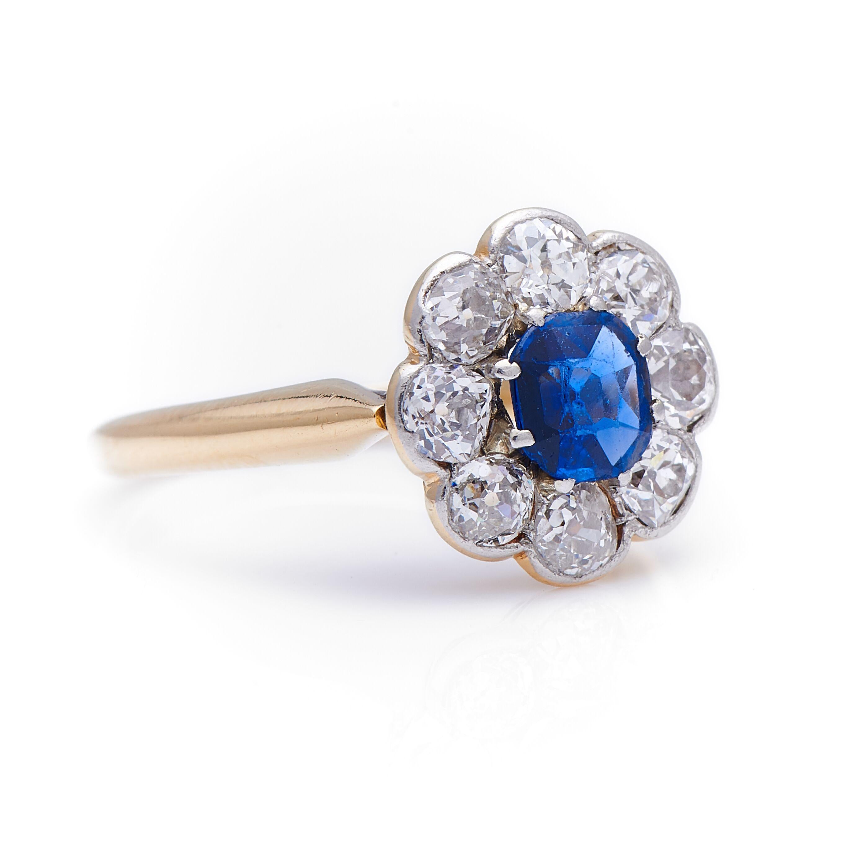 Sapphire and diamond cluster ring, circa 1900. A wonderful example of a classic engagement ring set to centre a stunning mid-blue cushion-cut sapphire enhanced by a boarder of old-cut diamonds. The diamonds are very bright, with plenty of sparkle,