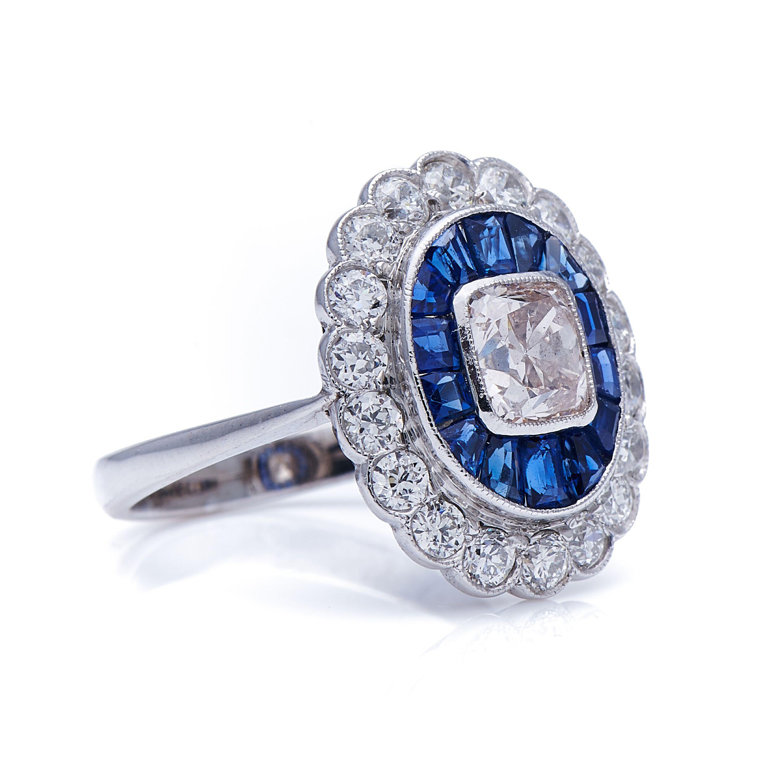 Diamond and sapphire ring. The centre of this glamorous ring is collet-set with a square cushion diamond weighing approximately 1.20 carats, within a border of radiating calibré-cut sapphires, to an outer floral border of circular-cut diamonds. The