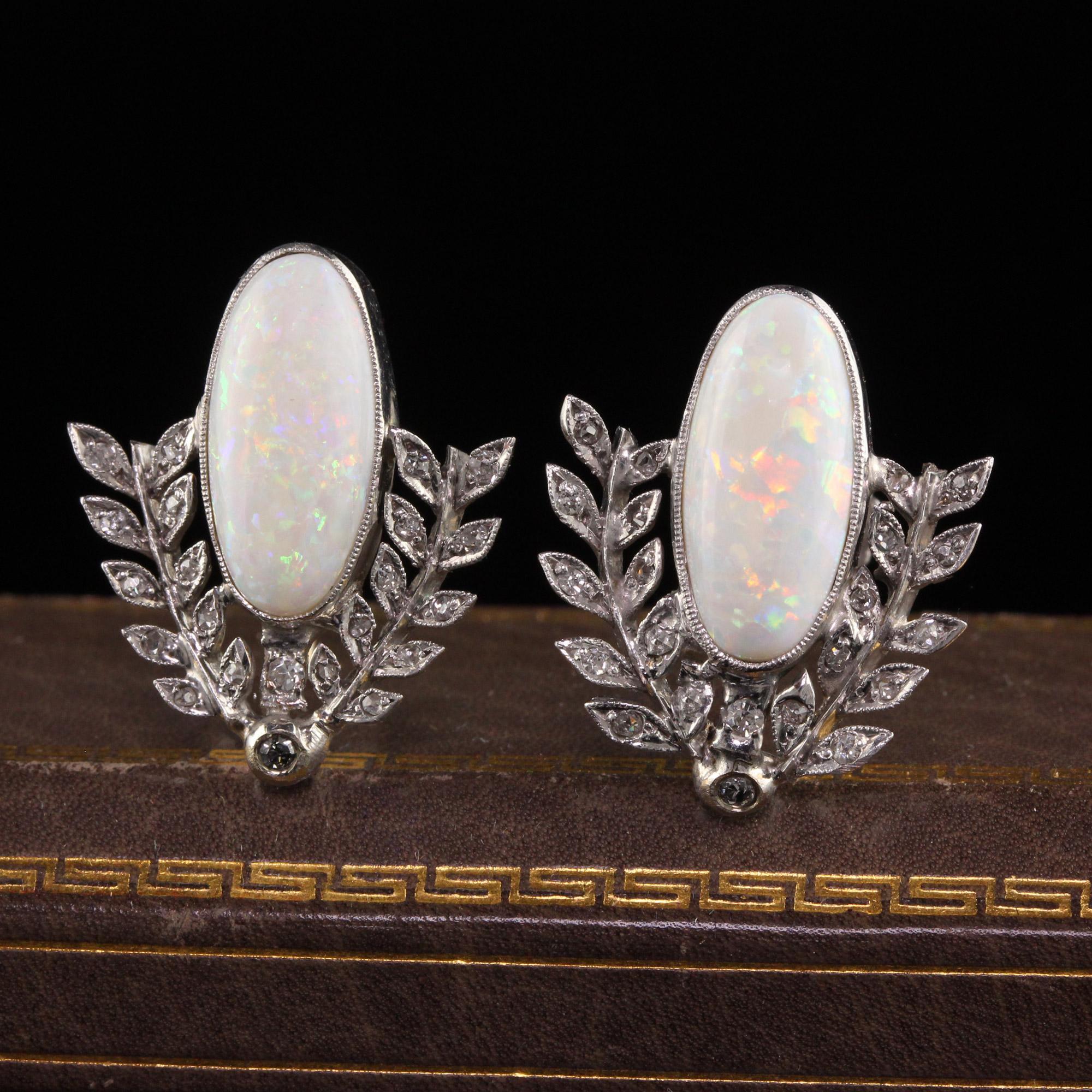 Beautiful Antique Art Deco 18K White Gold Opal and Diamond Wreath Earrings. This beautiful pair of earrings are crafted in 10k and 18k white gold. The earrings hold beautiful oval cabochon opals with a gorgeous play of color and surrounded by rose