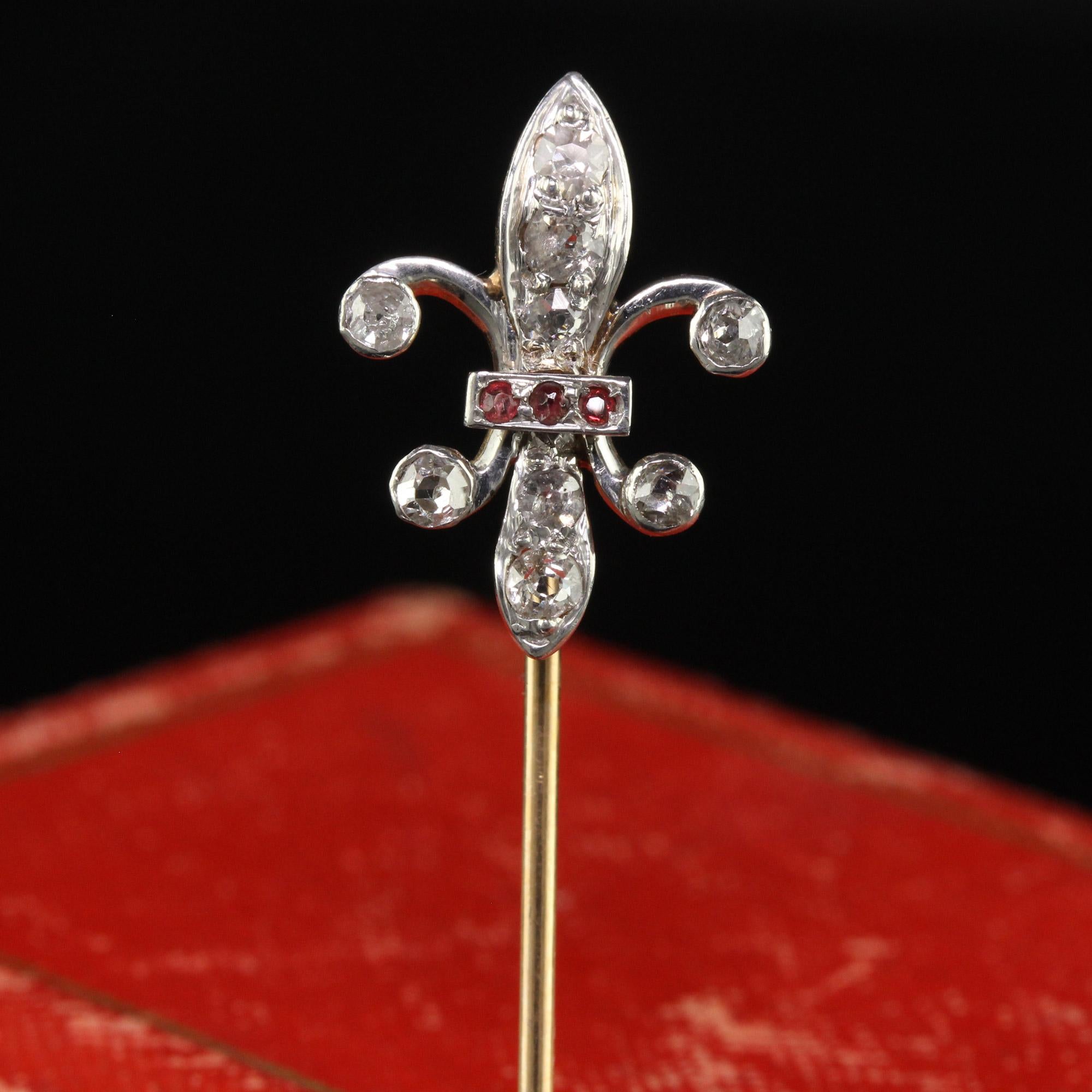 Beautiful Antique Art Deco 18K Gold and Platinum Fleur De Lis Diamond Stick Pin. This beautiful Fleur De Lis stick pin is crafted in 18k yellow gold and platinum. The top of the pin has old cut diamonds with a row of rubies in the middle. The pin is