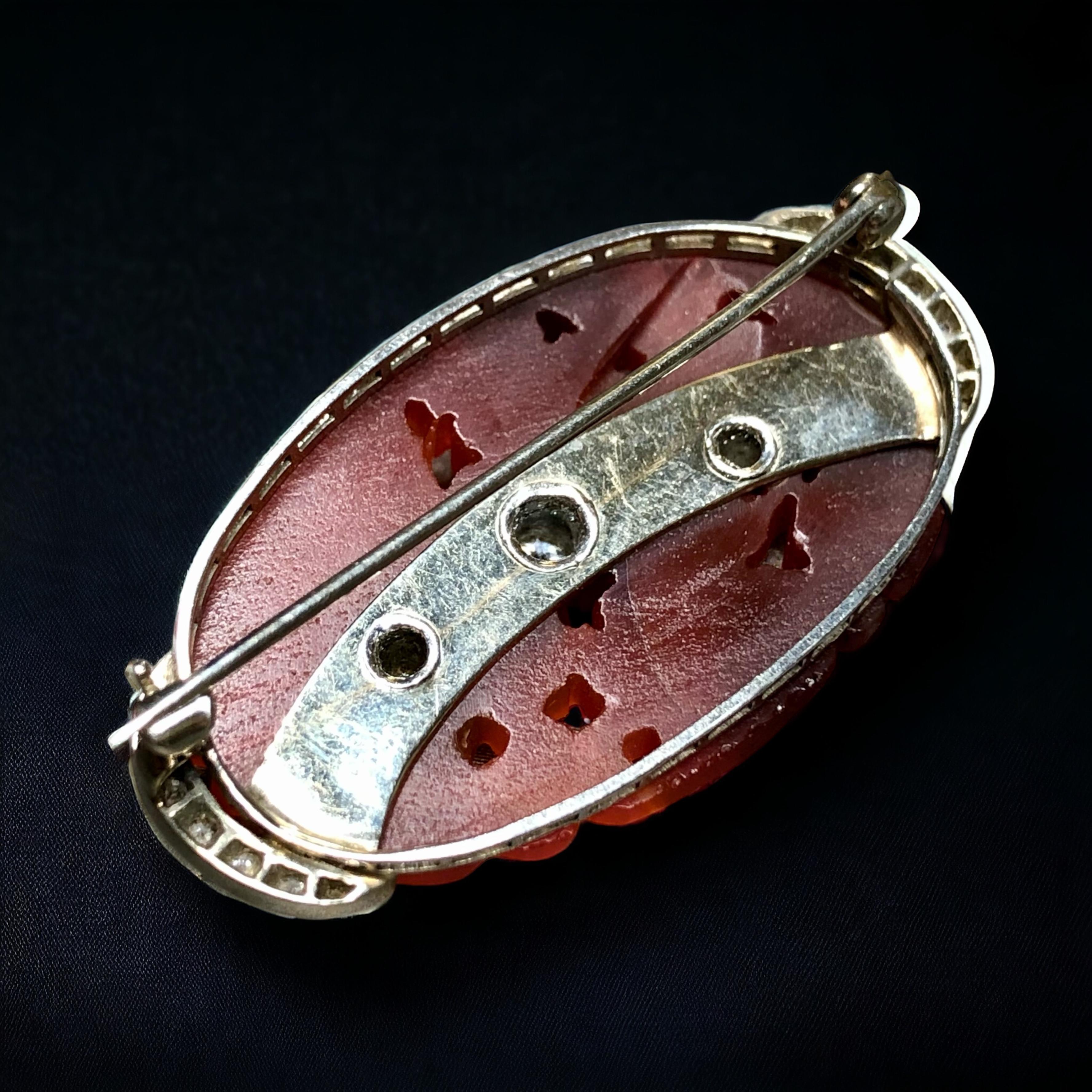 An original Art Deco era brooch done in 18K white gold and centered by an original piece of carved carnelian flanked and centered by old European cut diamond. Total approximate diamond weight is .57cttw and stones range G-I in color and Vs1-Si1 in