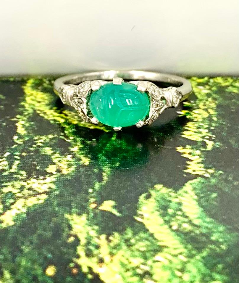 Fine Art Deco period 18K white gold, diamond, carved green onyx scarab amulet ring
Circa 1920
This beautiful ring features a vibrant, finely carved emerald green onyx scarab surrounded by twelve Old Mine cut diamonds in an attractive 18K white gold