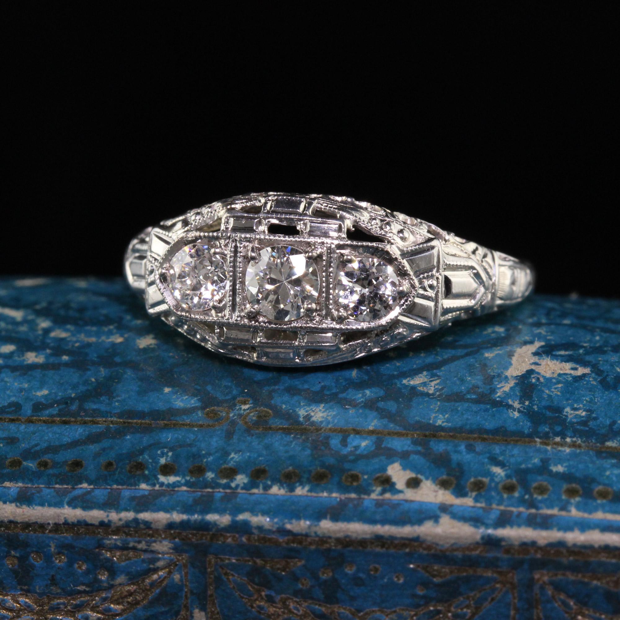Beautiful Antique Art Deco 18K White Gold Old European Diamond Three Stone Ring. This gorgeous ring is crafted in 18k white gold. The center holds three old european cut diamonds in a beautiful filigree mounting. It is in great condition.

Item