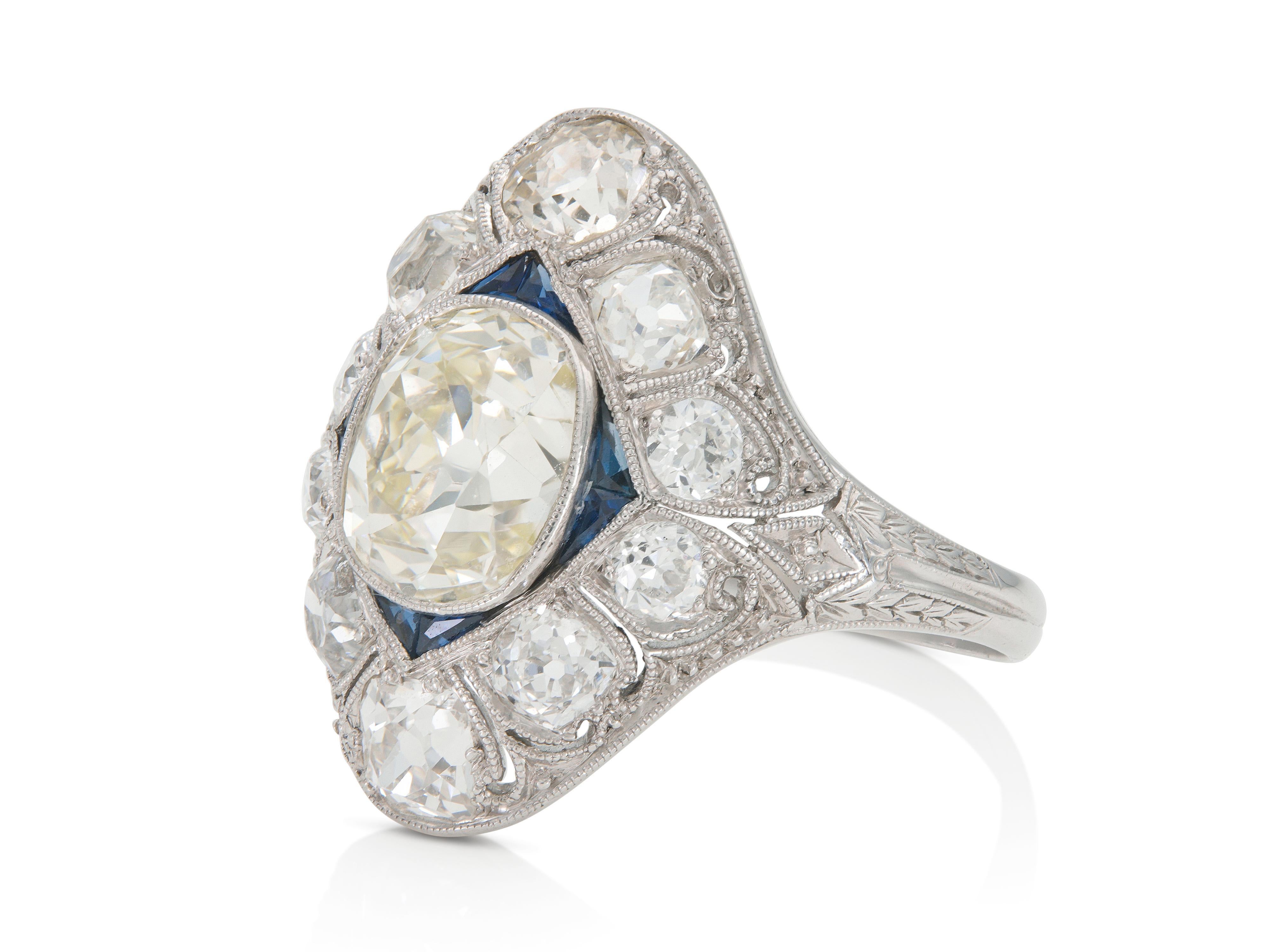 Finement réalisée en platine avec un diamant central de taille Old Mine pesant environ 2,50 carats, couleur O-P, pureté VS.
La bague est ornée de diamants plus petits, de taille Old Mine et Old European, pesant environ 2,00 carats au total, et de