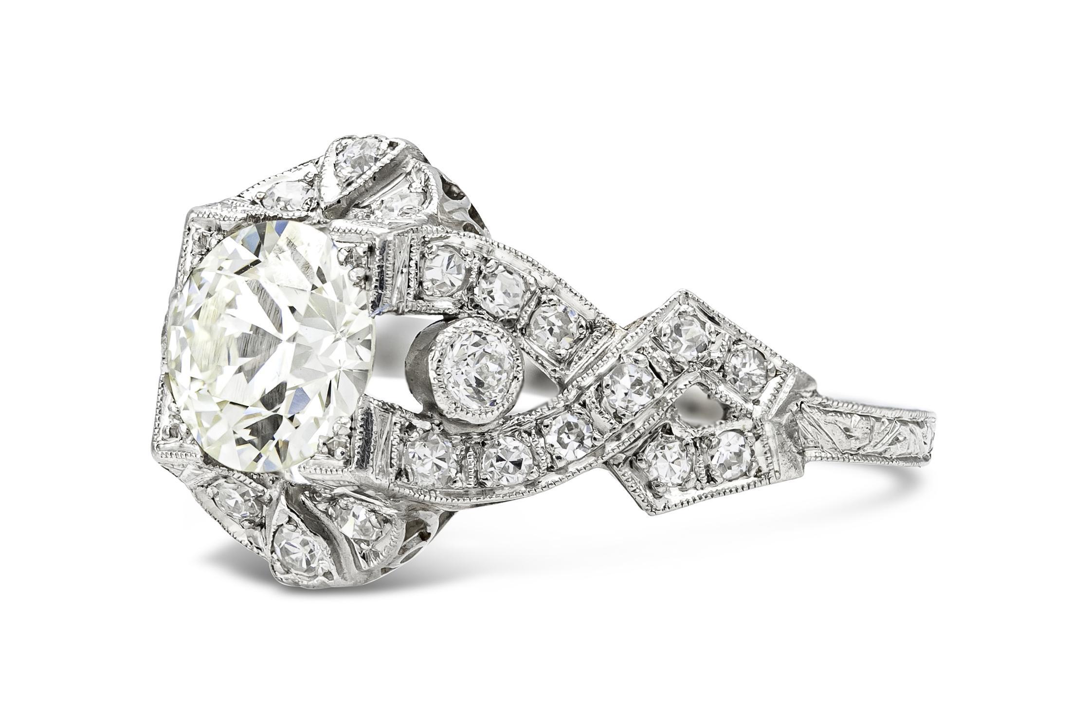 Fein in Platin gefertigt, mit einem Diamanten im alten europäischen Schliff mit einem Gesamtgewicht von ca. 1,20 Karat, Farbe L, Reinheit VS.
Der Ring weist zusätzliche Diamanten auf, die kunstvoll entlang der Fassung angeordnet sind und ein