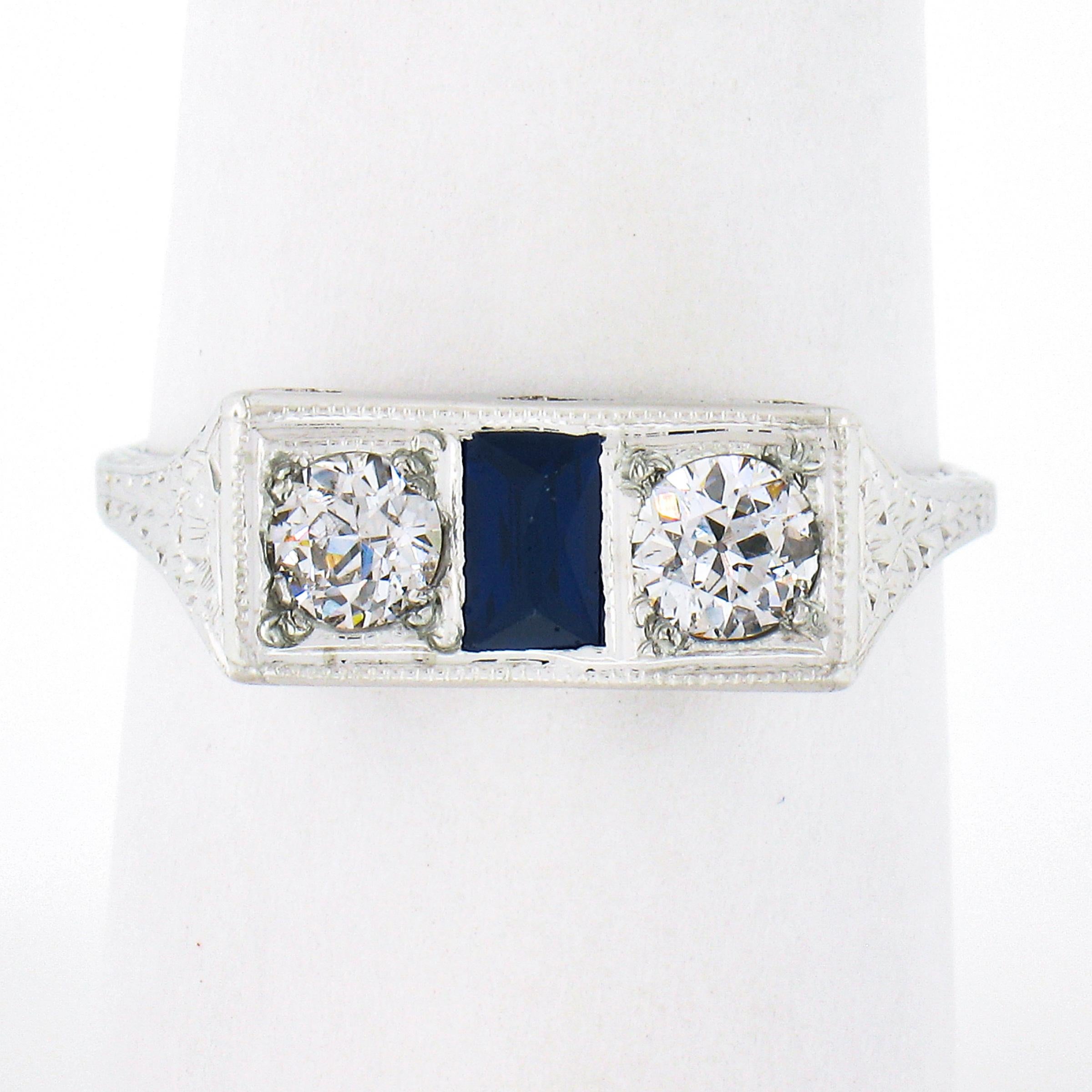 This gorgeous, all original antique moi et toi band ring was crafted in solid 20k white gold during the art deco period and features two fine quality old European cit diamonds flanked with a French baguette cut sapphire in between. These diamonds