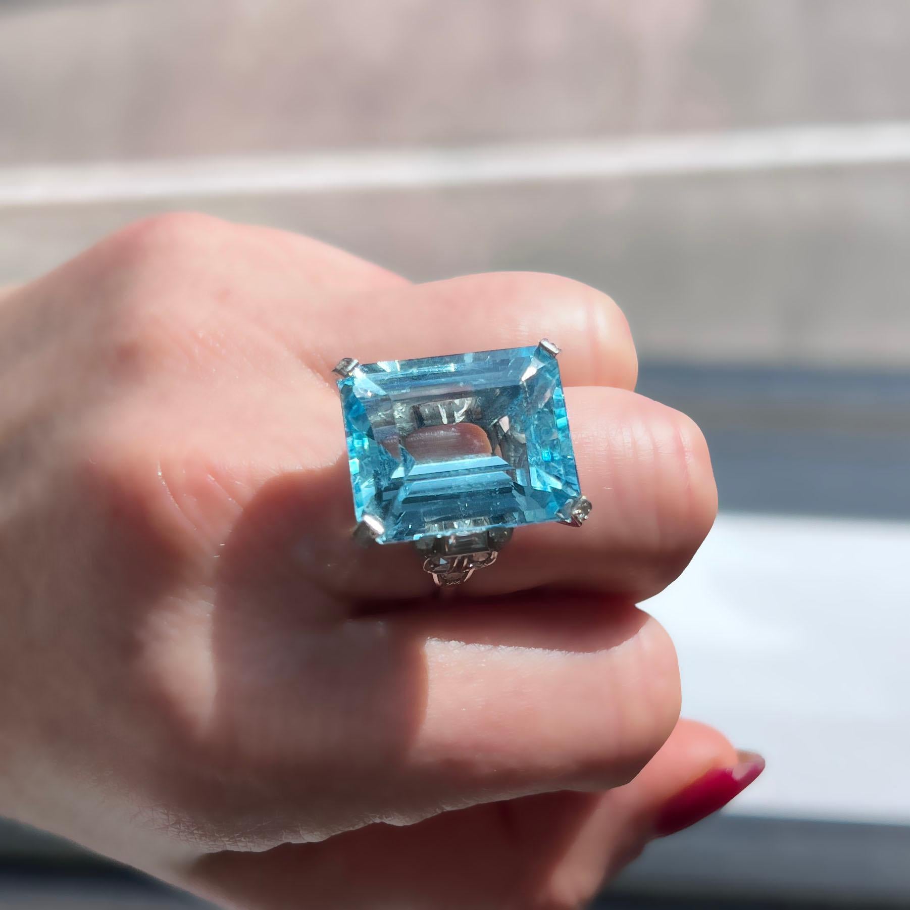 This exquisite antique Art Deco ring features a breathtaking 25.25-carat bright blue aquamarine set in a finely crafted platinum mounting. Accented by 16 sparkling diamonds totaling 0.65 carats, the intricate geometric design highlights the elegance