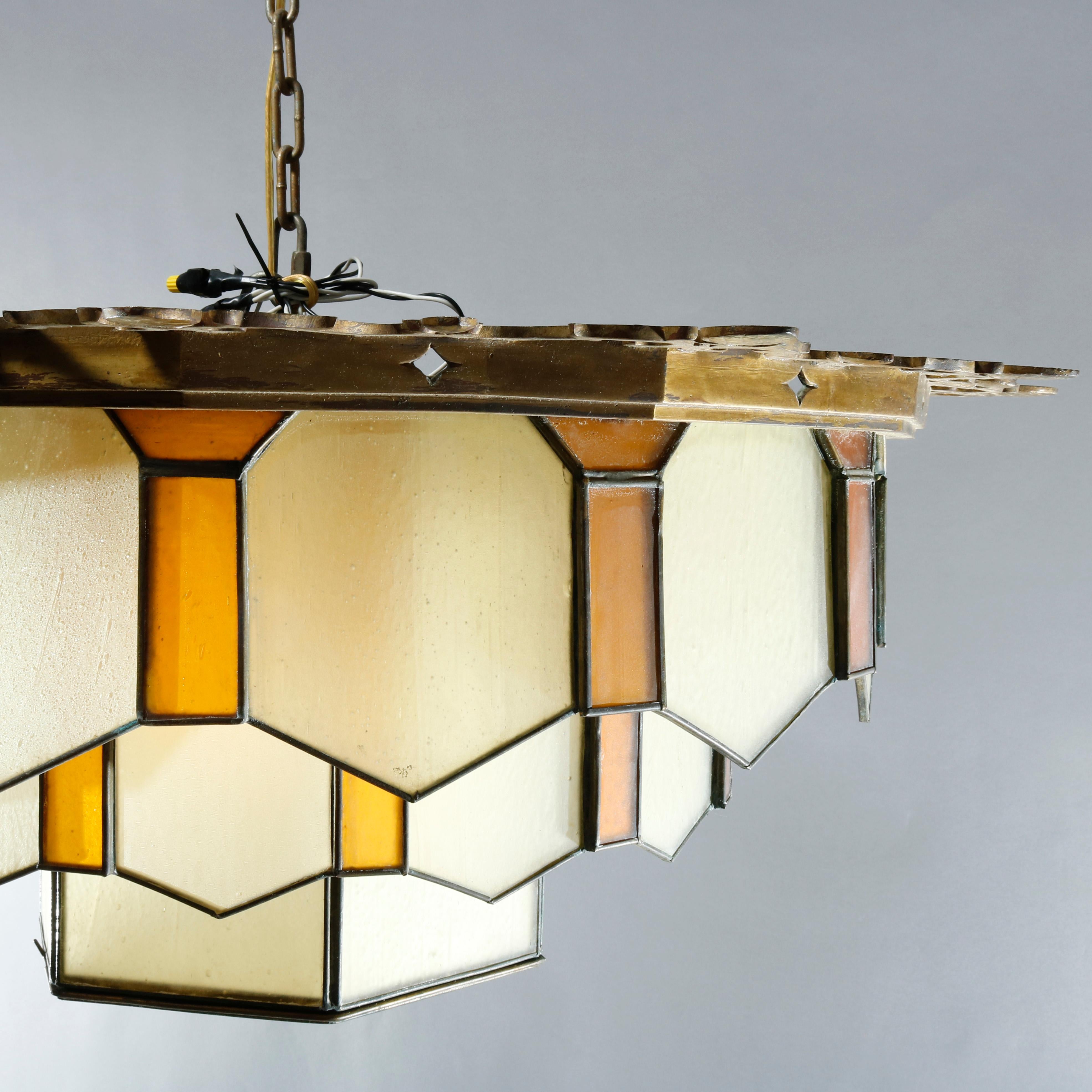 An antique matching pair of Art Deco theatre ceiling fixtures offer stylized wedding cake form in leaded and paneled amber and frosted glass having cast, pierced and gilt foliate frame, c1920.

Measures: 64