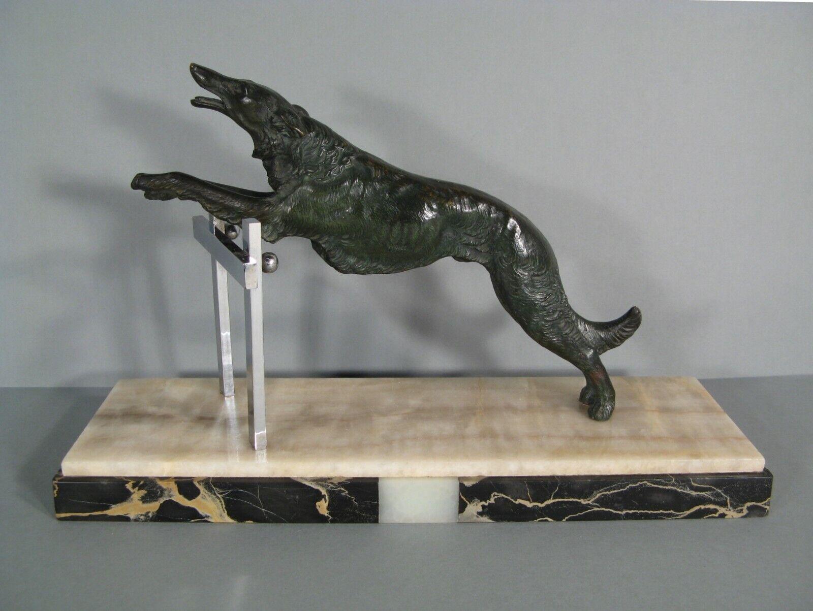 This exquisite Art Deco sculpture, crafted in patinated bronze, depicts a greyhound gracefully leaping over an obstacle.

Style: Art Deco
Material: Patinated bronze, with a marble base and a chromed brass obstacle
Patina: Dark green with golden