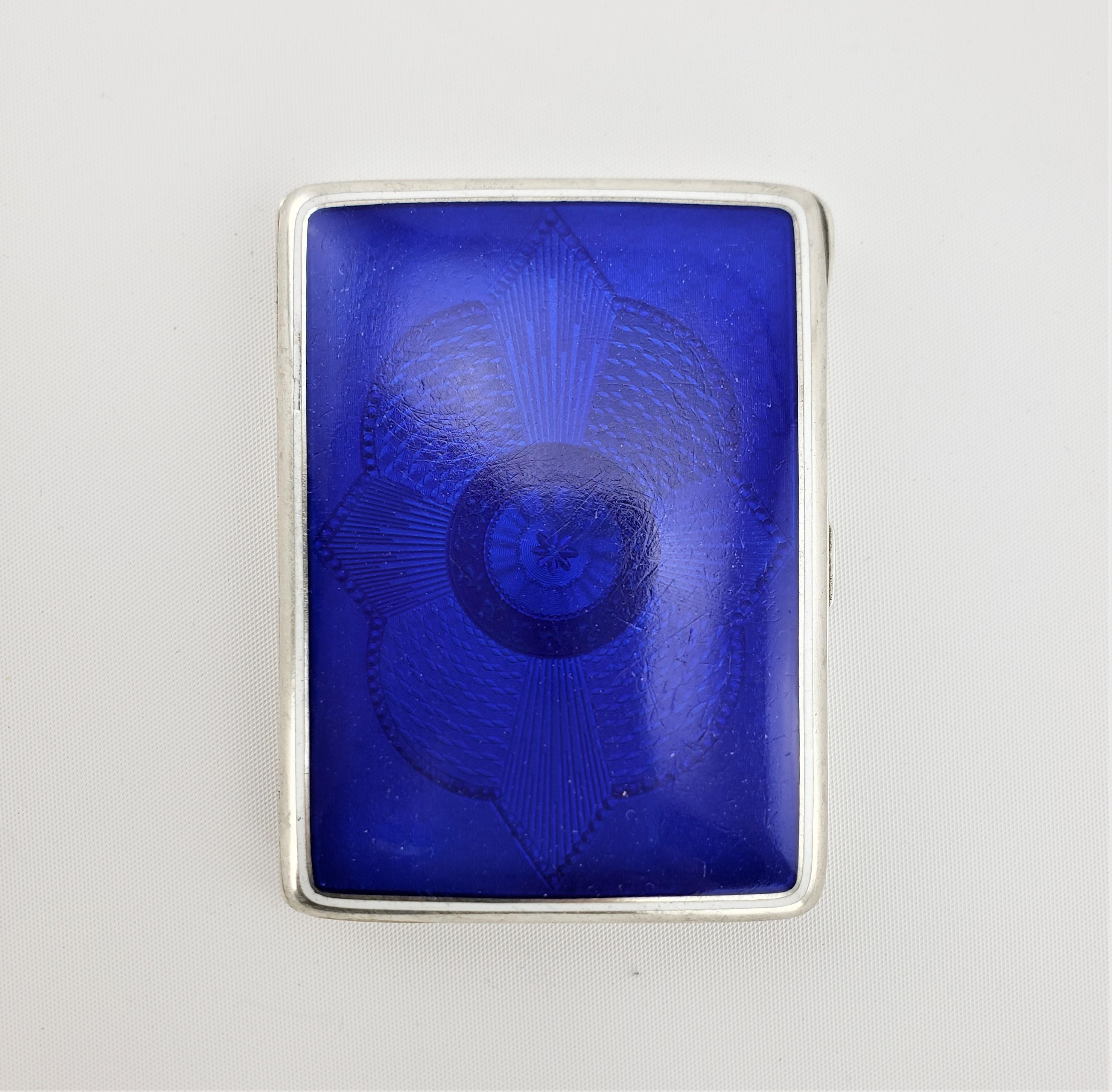 This silver and enamel cigarette case is hallmarked by an unknown maker and is presumed to have been made in Austria in approximately 1920. The case is composed of .830 silver and has a very bright cobalt blue enameled panel on the front with an