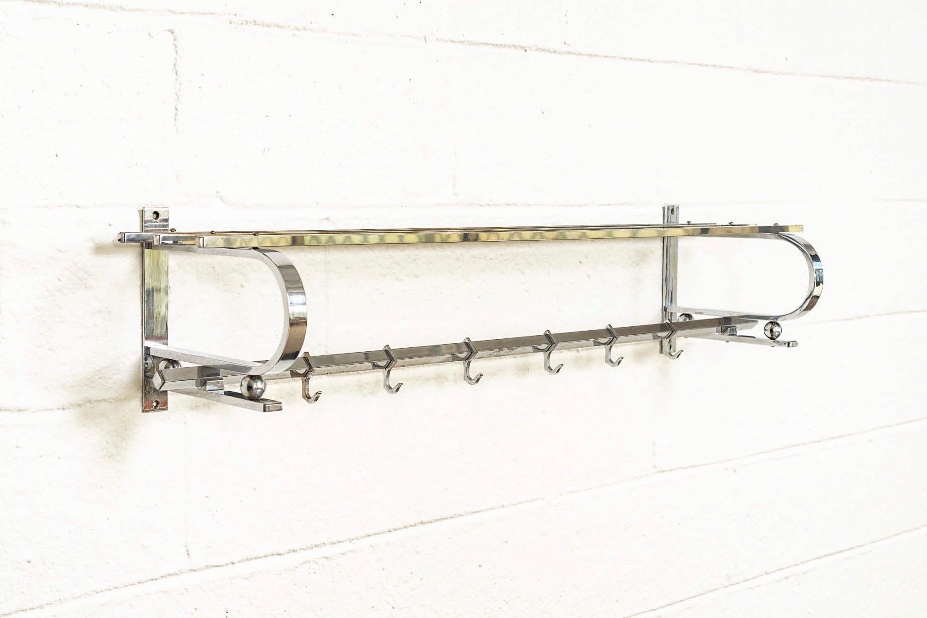 This vintage antique Bauhaus / Art Deco hanging coat and hat rack was made in Germany circa 1930. Constructed of chrome-plated steel, the sleek, modernist design features a three bar upper shelf and one lower bar with six adjustable sliding hooks.