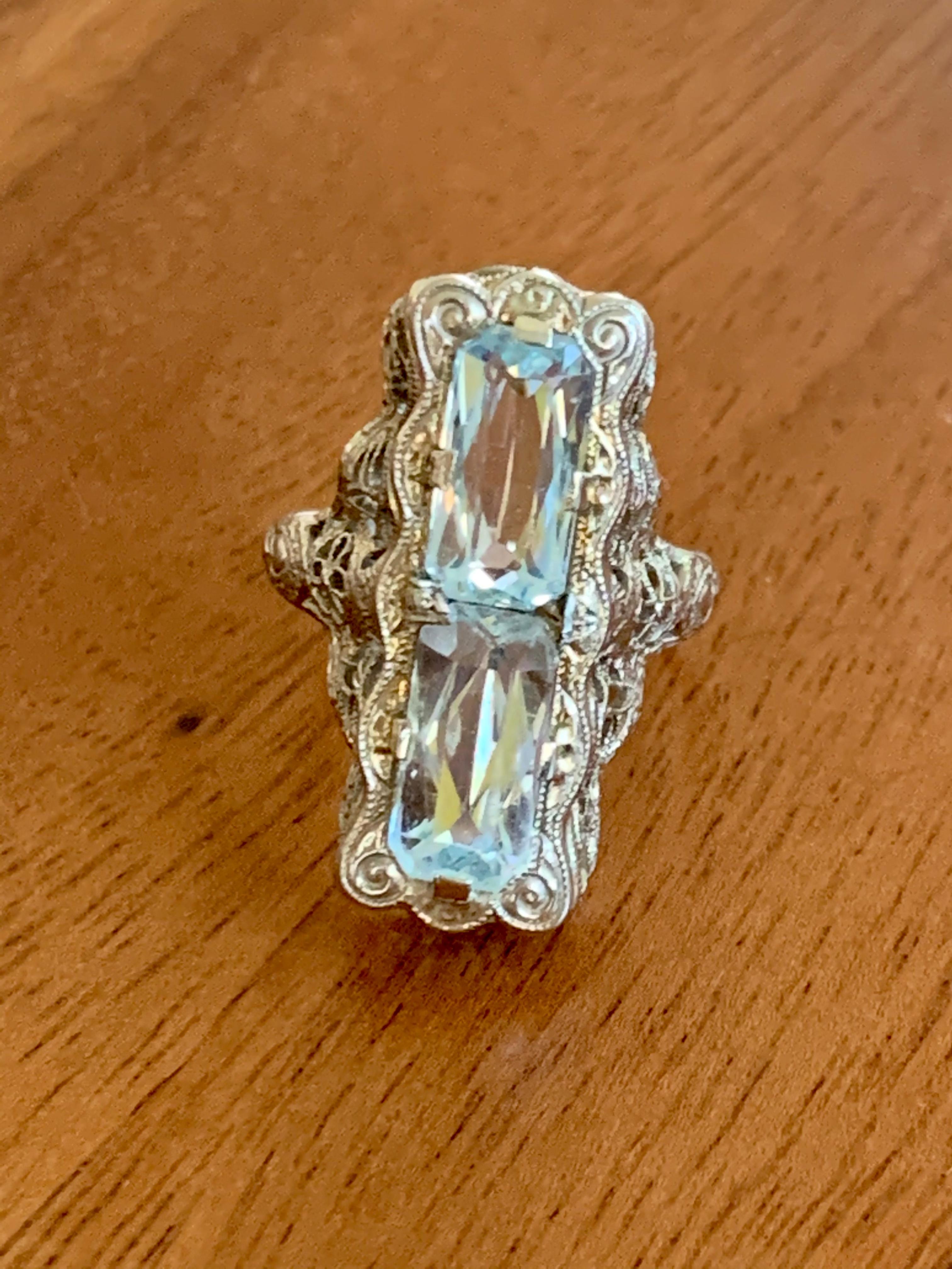 This beautiful, antique ring features two Aquamarine stones which are emerald cut and approximately 9 x 5mm in size.  

The ring is stamped 
