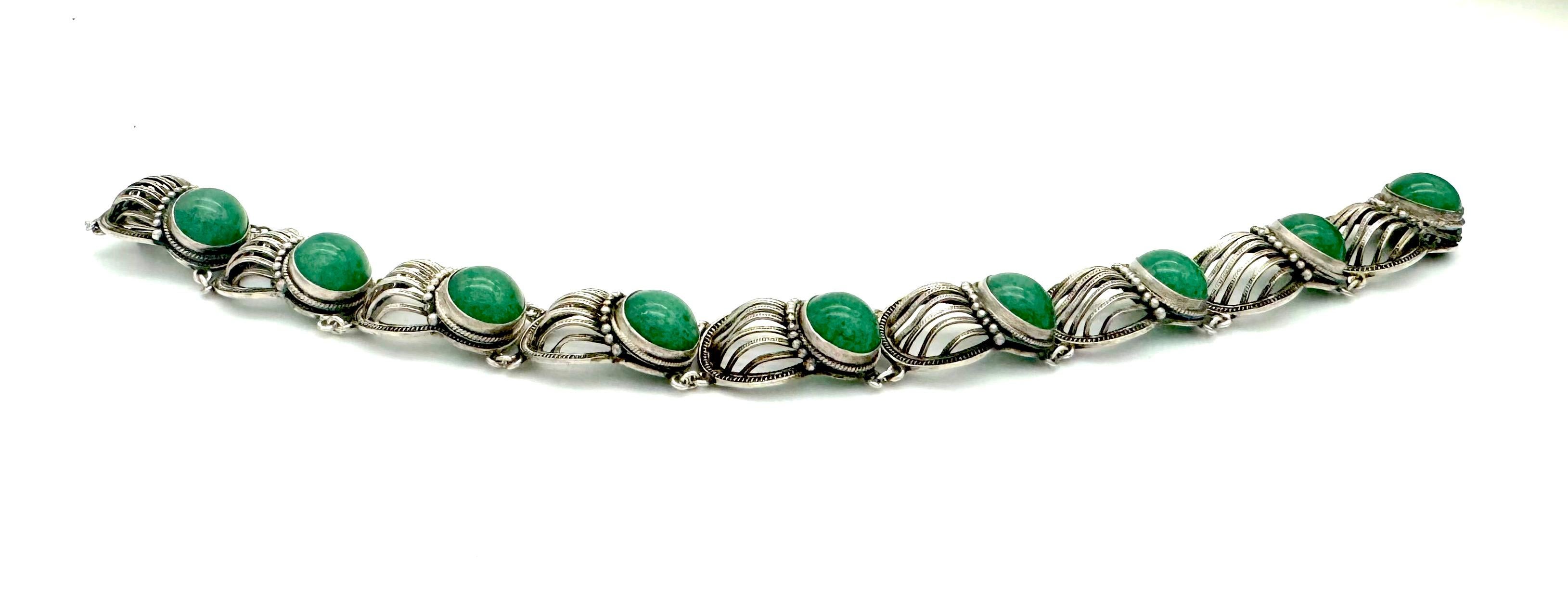 This unusual and delicate Art Deco silver bracelet was handcrafted in 1920 ca. Nine stylized shell ornaments, one of them being the clasp alternate with nine jade cabochons mounted in silver settings. The bracelet is marked silver on the inside of