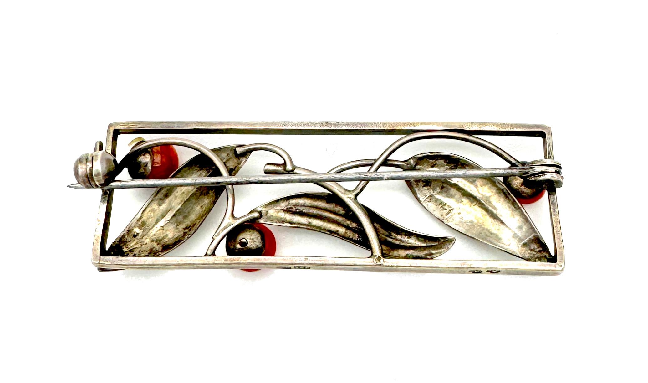 This brooch is designed in the Austrian secessionist style popular in the first quarter of the 20th century. Within a rectangular silver frame we see stylized flower buds made out of different sizes of corallium rubrum beads and silver leaves with a