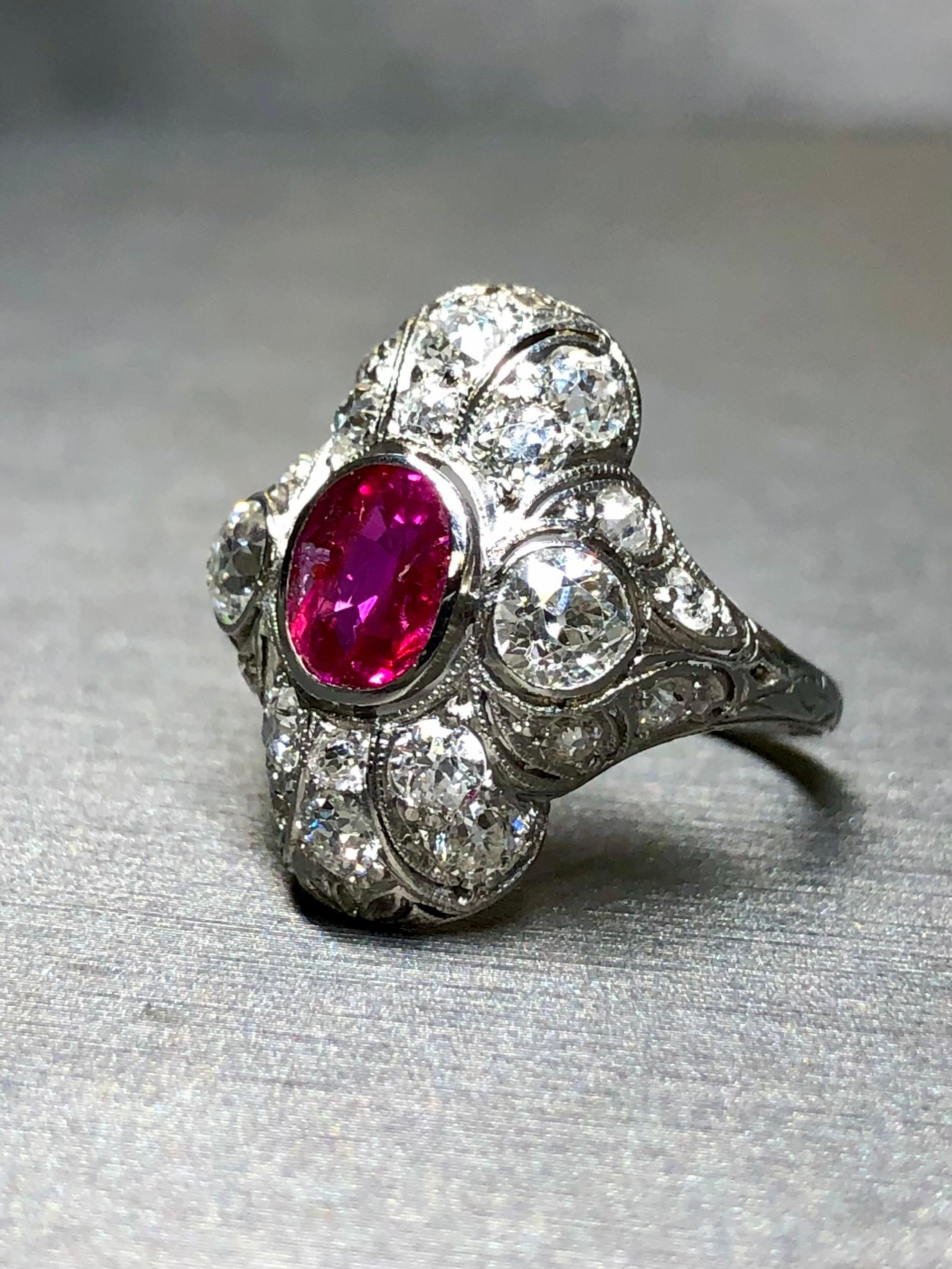 An exceptional, original Art Deco ring done in platinum and centered with a 1.02ct oval natural no heat Burmese ruby exhibiting exceptional color with an ever so slight purplish undertone being almost pure vivid red. Surrounding the center stone