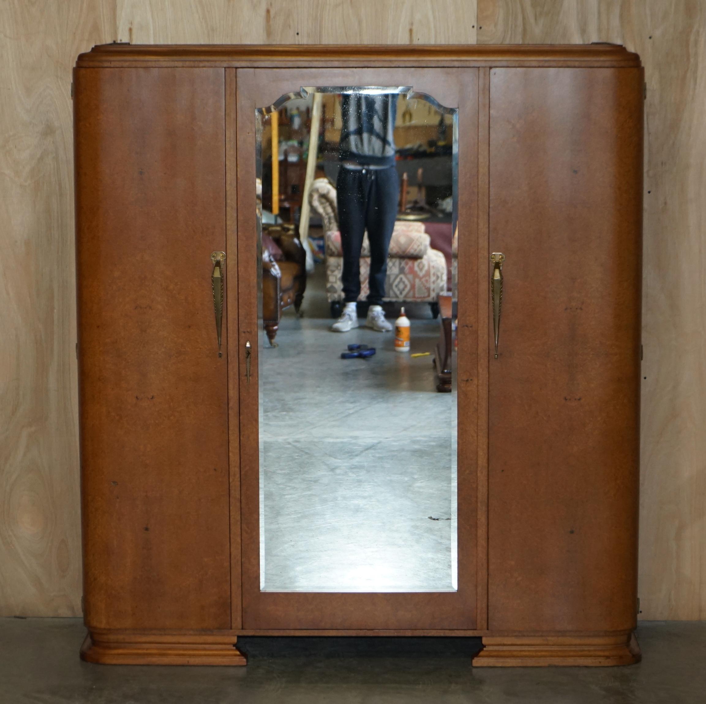 Nous sommes ravis d'offrir à la vente cette superbe armoire Art Déco en loupe d'érable à trois niveaux avec une grande porte centrale en miroir sur toute la longueur, qui fait partie d'une petite suite.

Il s'agit d'une pièce décorative de très