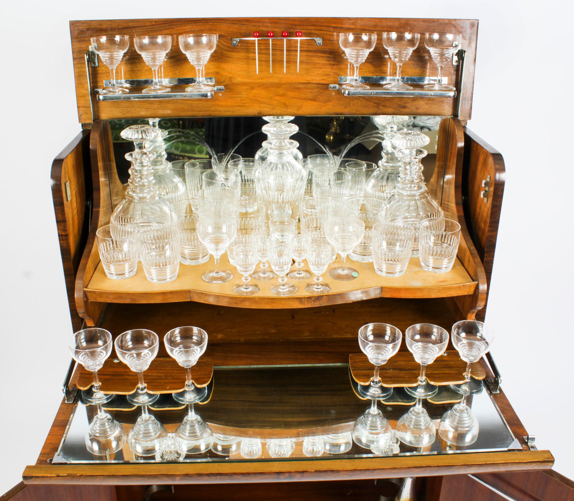 This is a fantastic antique Art Deco burr walnut cocktail cabinet, complete with crystal glassware, circa 1920 in date. 
 
It is of rectangular form, made in beautiful burr walnut, the upper part opens to reveal a fitted mirrored interior with