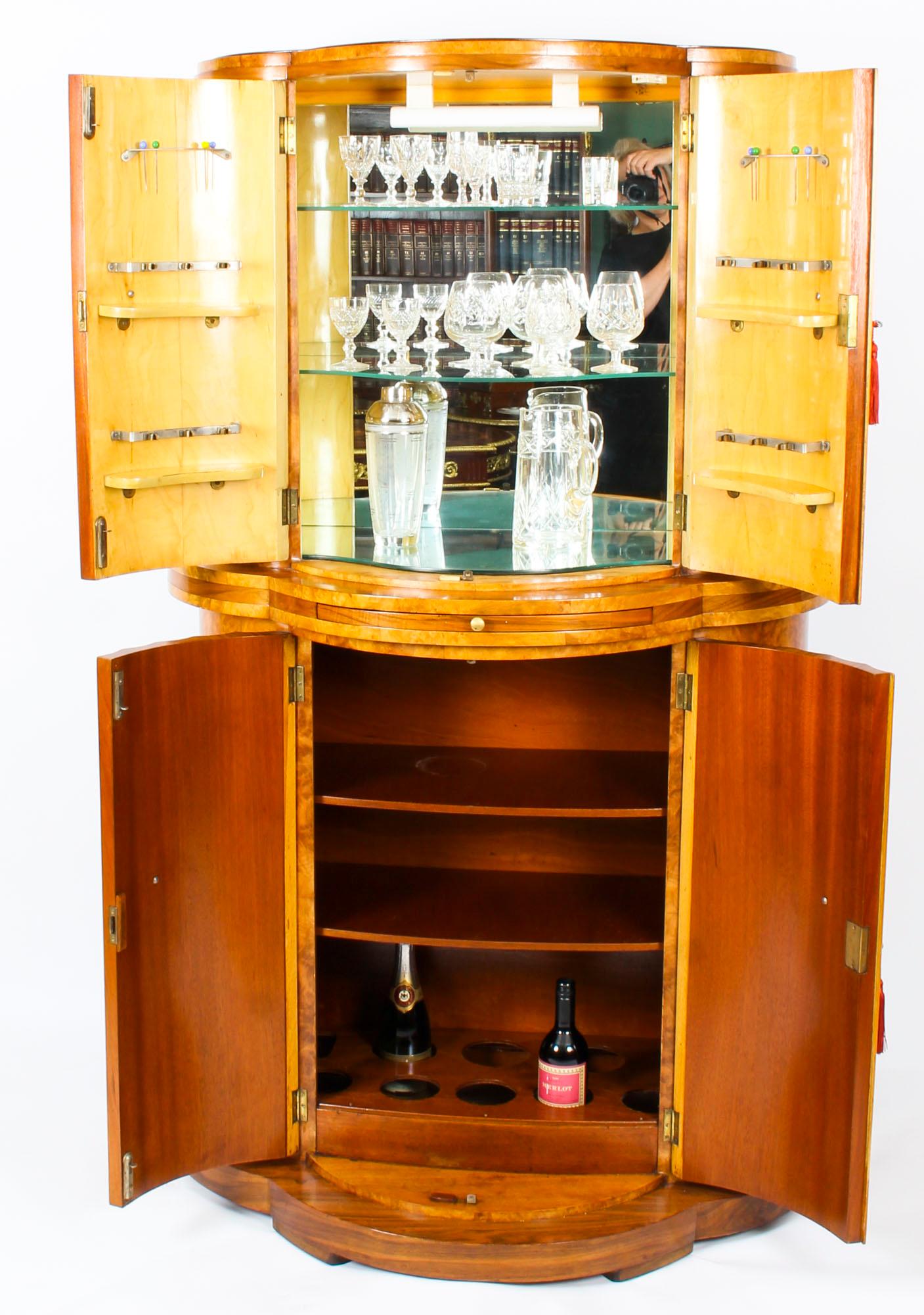 This is a fabulous antique demilune Art Deco burr walnut cocktail cabinet, circa 1930 in date by Harry & Lou Epstein.

The upper part comprises a pair of demilune fluted doors that each has two beautiful small shelves with clips for glasses on their