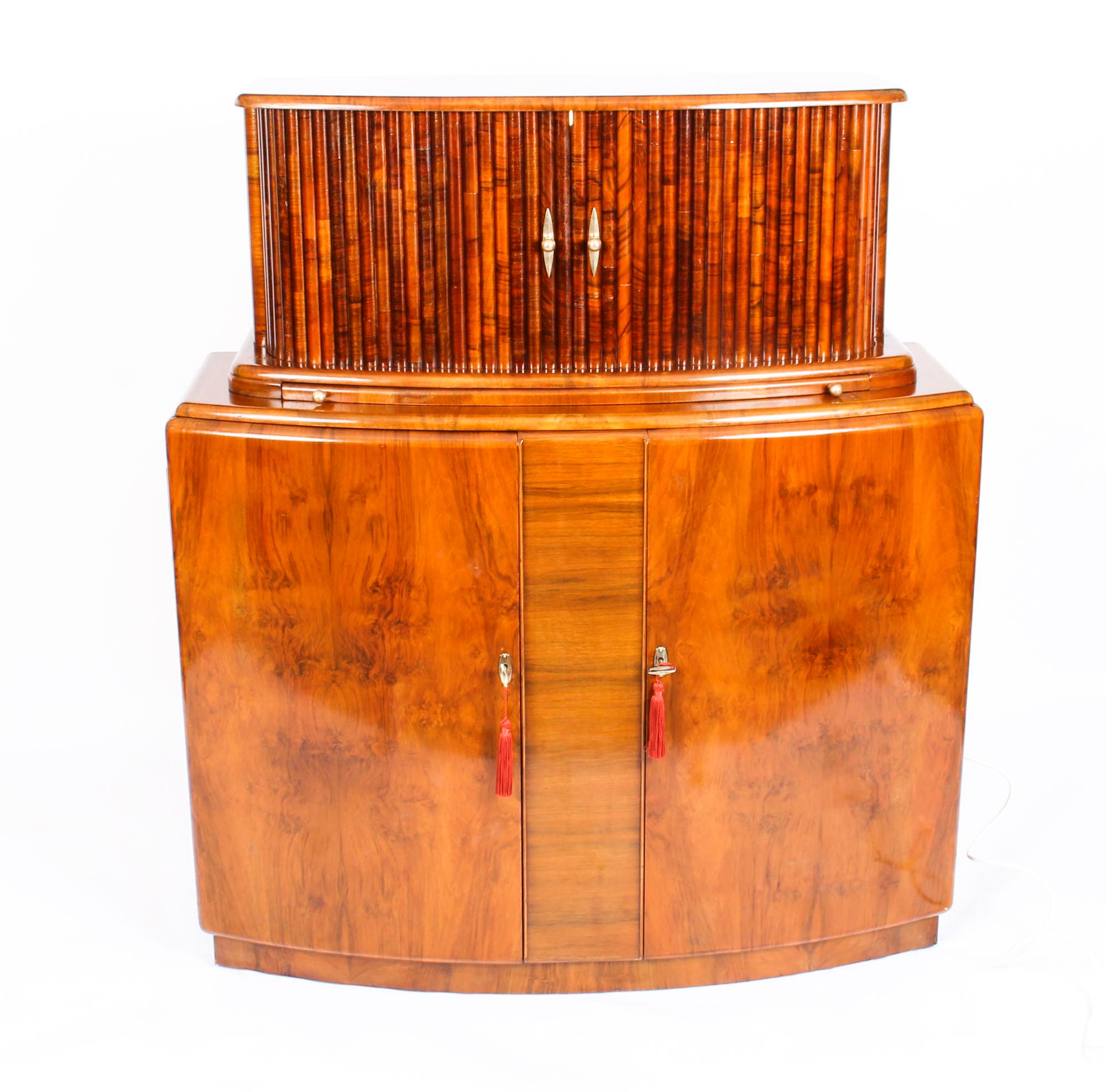 This is a fantastic antique Art Deco burr walnut bow fronted cocktail cabinet, circa 1930 in date and in the manner of Epstein.

This beautiful cabinet's upper part comprises a pair of tambour sliding doors enclosing a striking fitted decorated