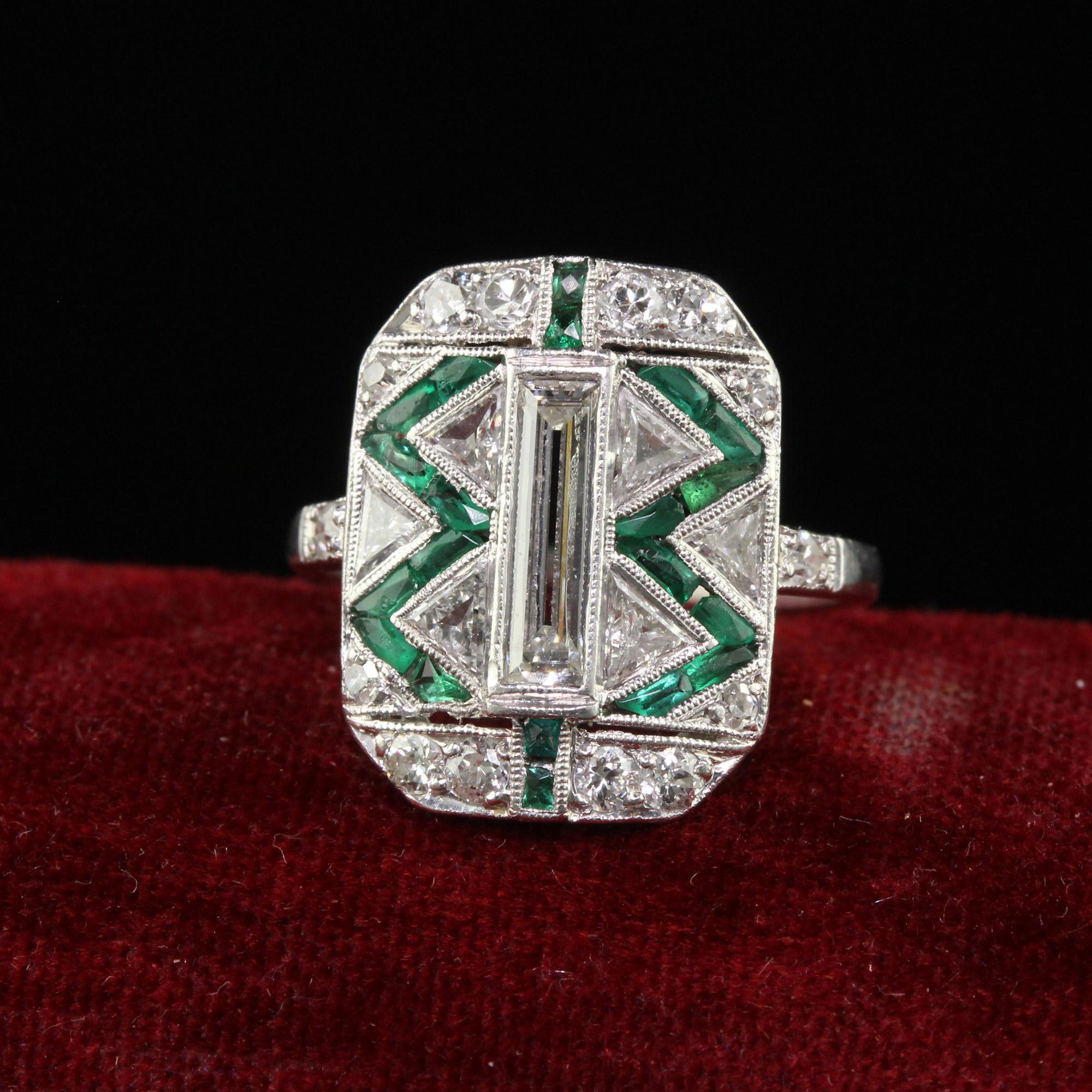 Magnifique bague de cocktail Art Deco Cartier Old Baguette Diamond and Emerald. Cette incroyable bague de Cartier est réalisée en platine. La Nature est composée d'un diamant baguette allongé au centre, de trois diamants trillion de taille ancienne