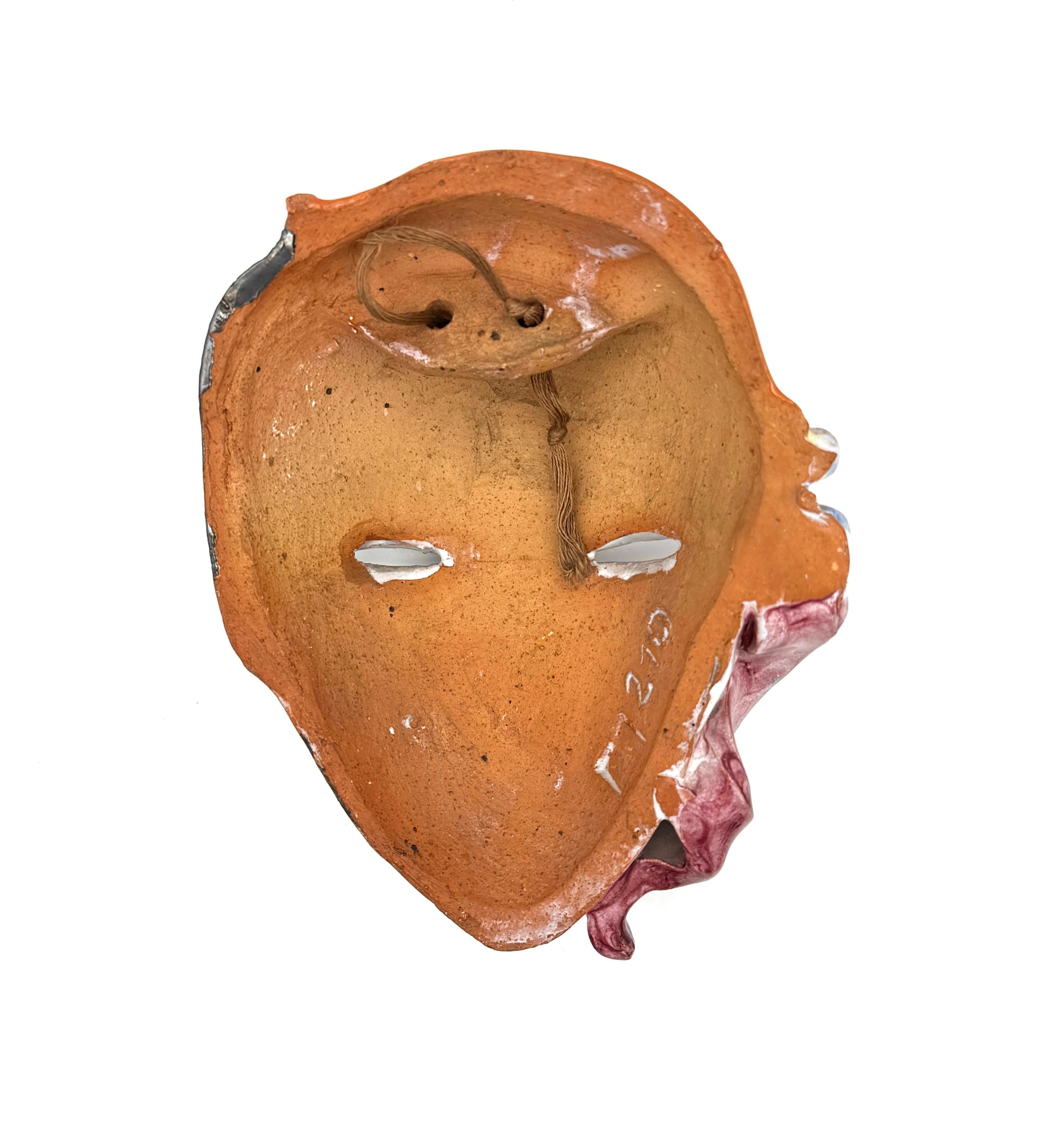 The ceramic wall masque was handcrafted in 1920 ca. The masque in the shape of a stylish young lady with delicately modelled face is wearing a fashionable little red hat on the side of her head. Her black hair is styled in typical 1920's fashion.