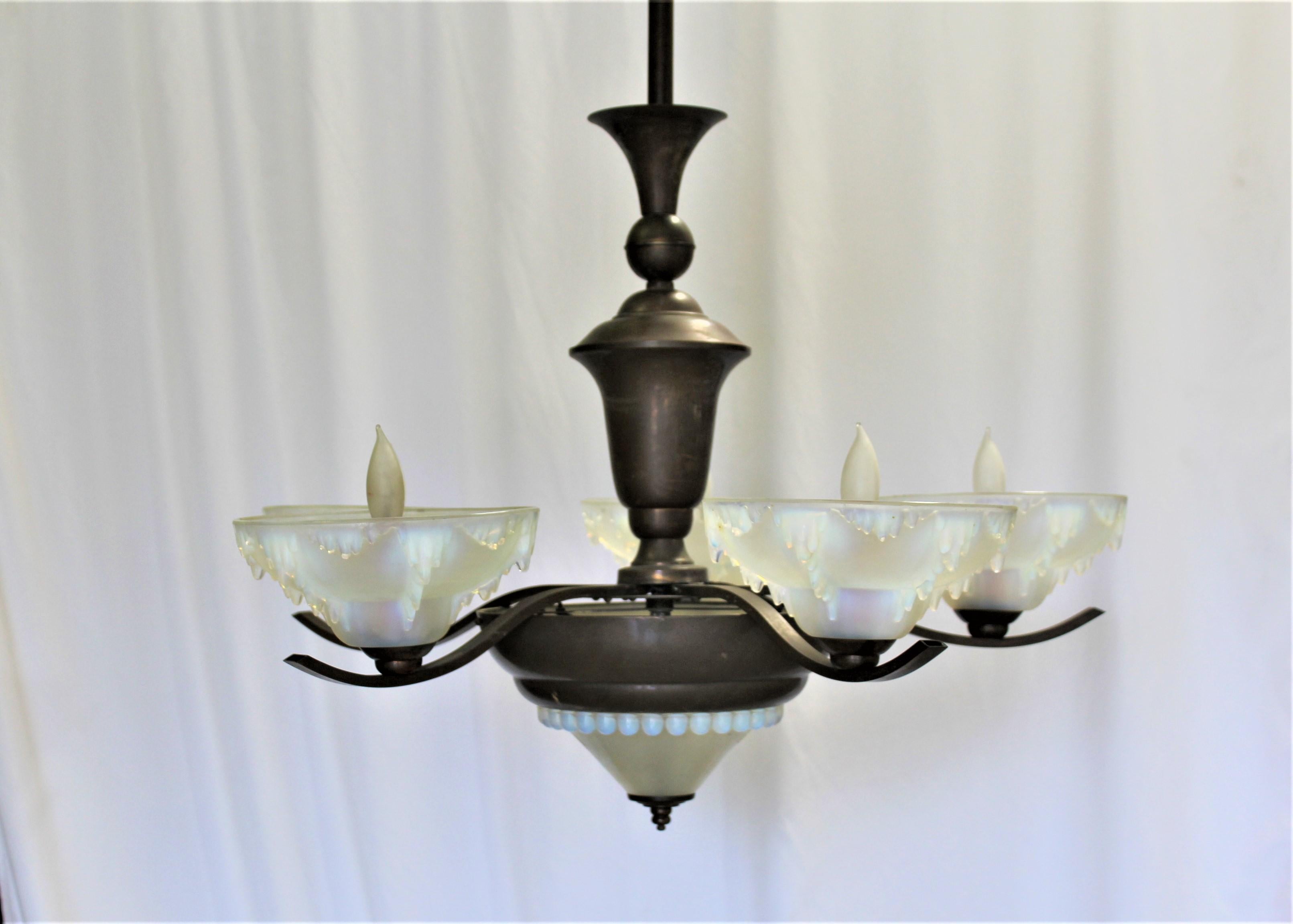A real Art Deco chandelier from France. Has 5 arms with Vaseline glass shades .The bottom center glass is designed with balls around and in Vaseline glass . The main body and arms are finished in a Bronze /Copper color. The other glass shades are