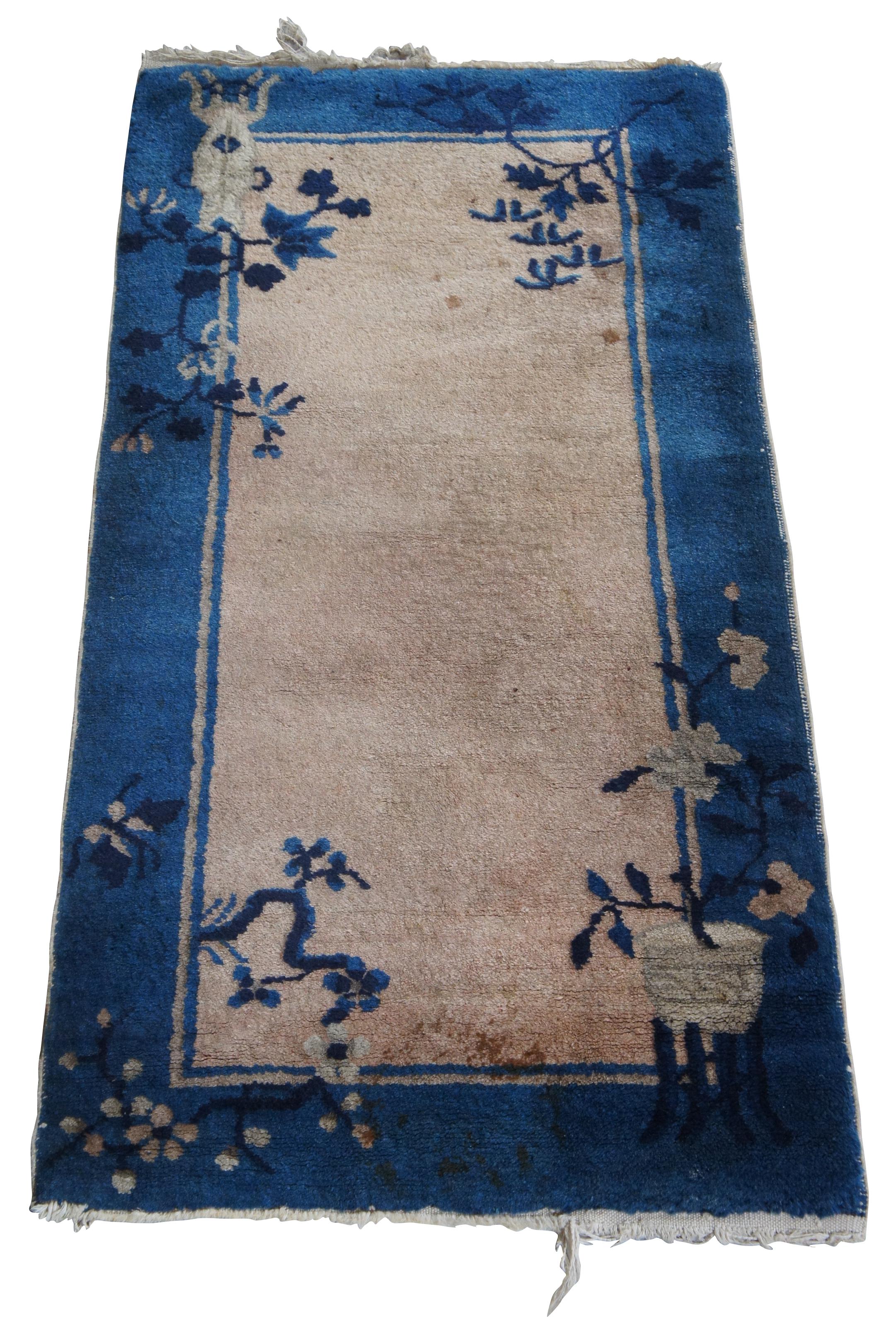 Antique chinese floral rug or carpet featuring flower filled vases on stands against a salmon pink ground with blue boarder.
  