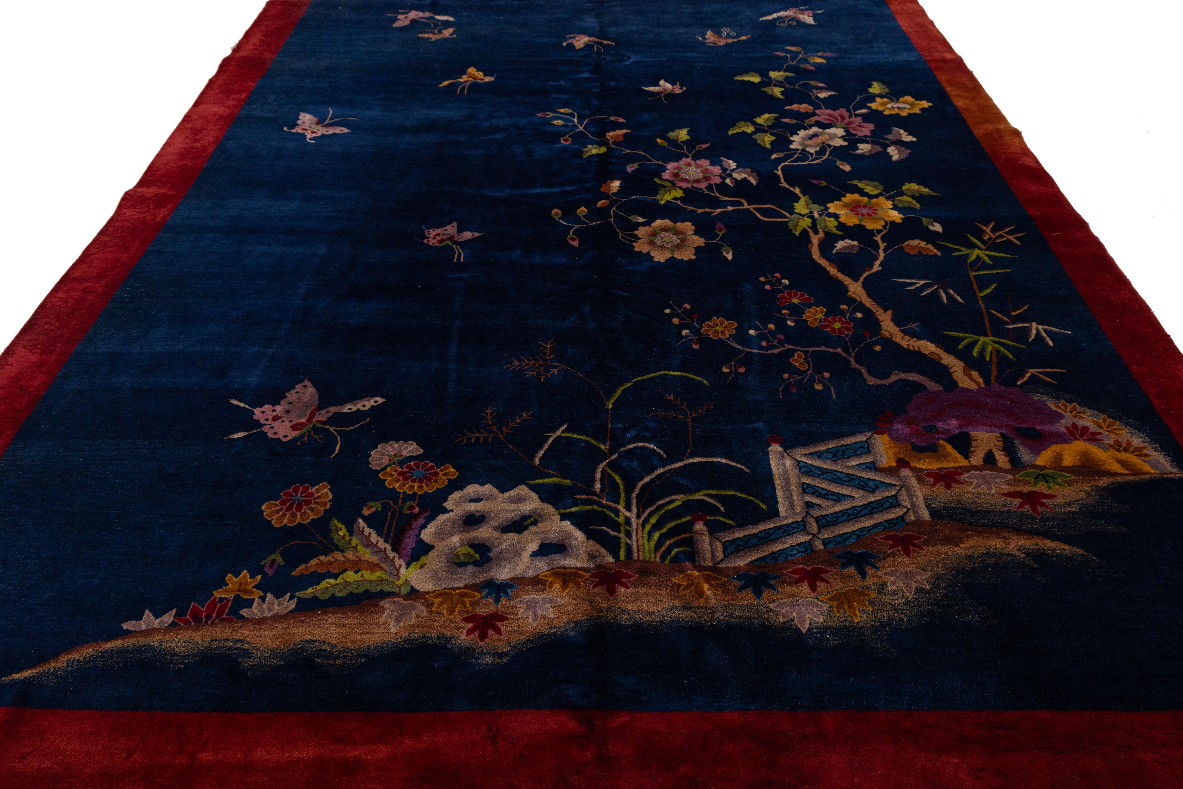 Magnifique tapis chinois antique Art Déco en laine nouée à la main avec un champ bleu. Ce tapis chinois a un cadre rouge, des accents multicolores dans un magnifique motif floral chinois. 

Ce tapis mesure : 9' x 11'7