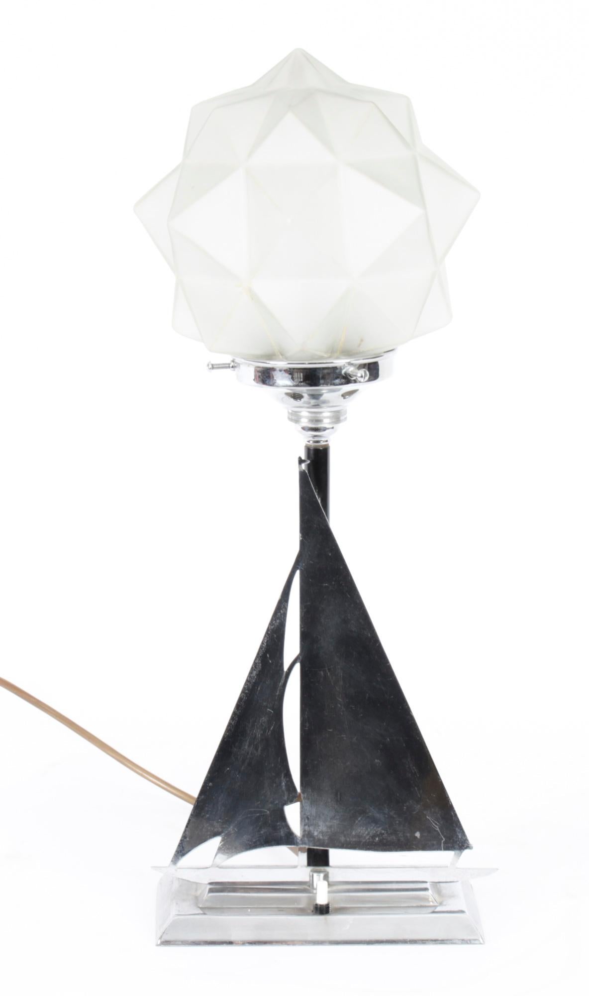 This is a beautiful antique Art Deco lamp depicting a chrome yacht with sail, circa 1920 in date.
 
This lamp has a stencilled cut chrome plated yacht design on a stepped rectangular base and features a multifaceted frosted glass globe shade.
