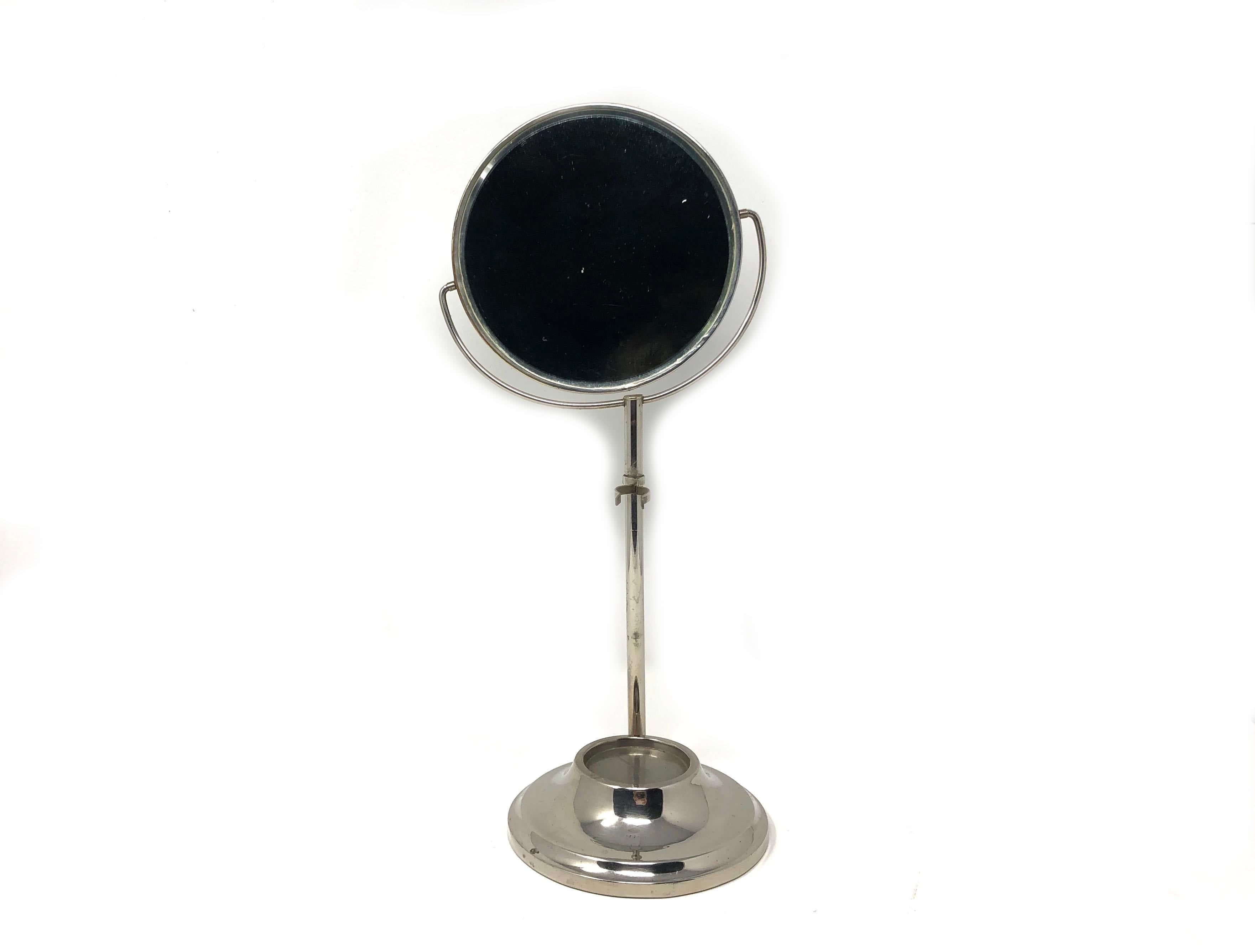 Handsome antique chrome shaving mirror on stand with hanging razor holder and inset shaving cup holder. Elegant with lovely shape. Finish appears to be chrome. Very heavy as there is cast iron in the base. Mirror tilts up and down. 

The base is