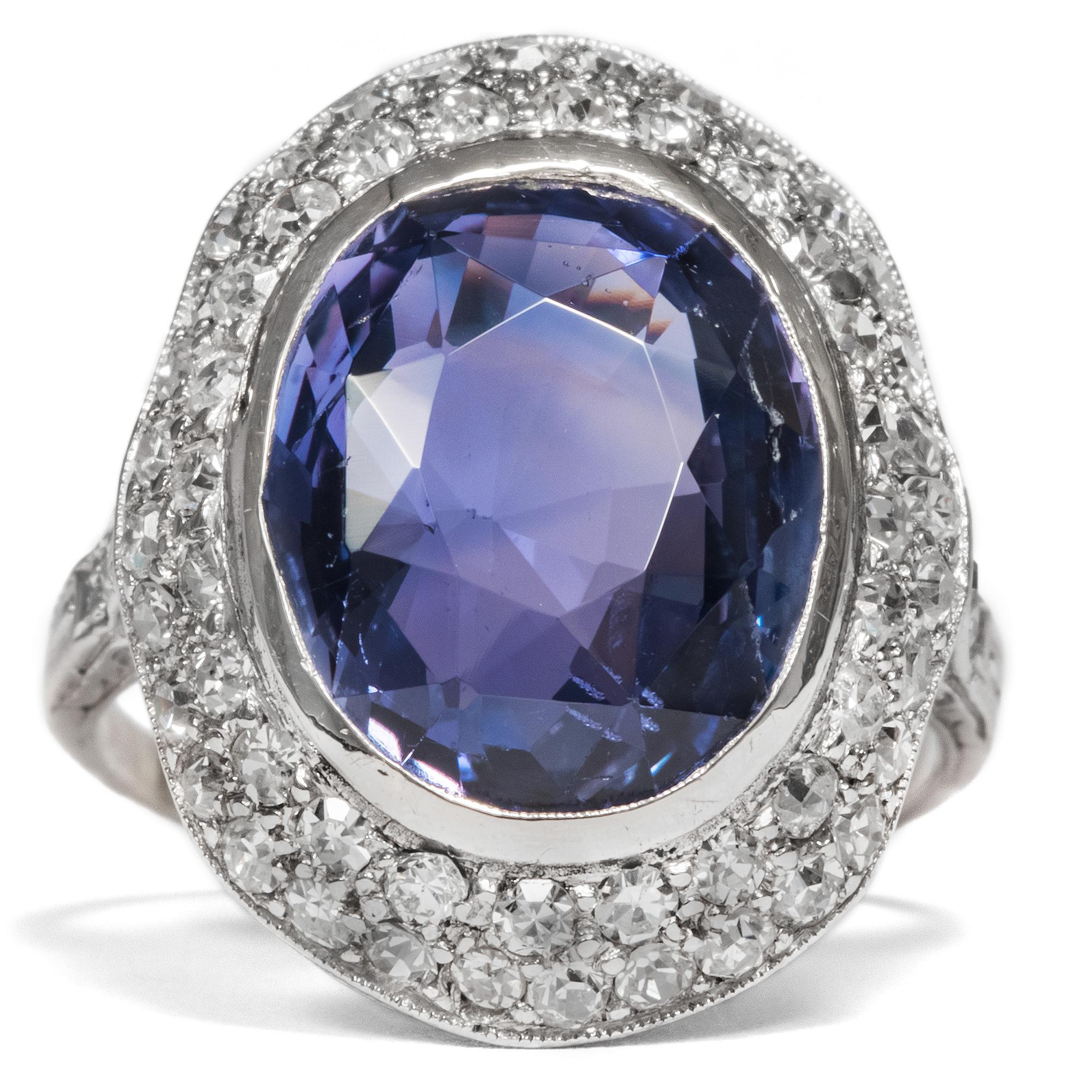 A natural, untreated ('no heat') blue sapphire with a delicate tint of violet is the focal point of this spectacular Art Déco ring. The precious gemstone weighs in at approx. 8.50 ct and is presented in a unique, beautifully faceted cut. Its