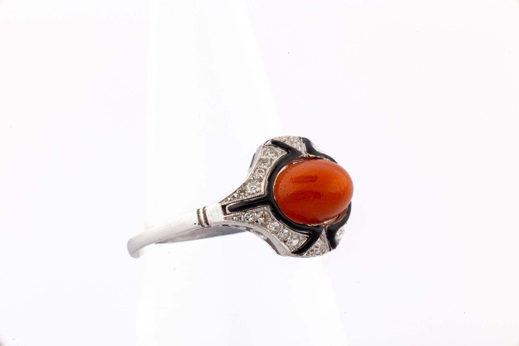 Displaying the Art Deco Banner of color contrast and geormetry a delectable coral diamond enamel ring c..1920 is a treat to see. The oval coral is framed with black enamel showing off its imposing color and dome shape.. Sorrounding the ring are rose