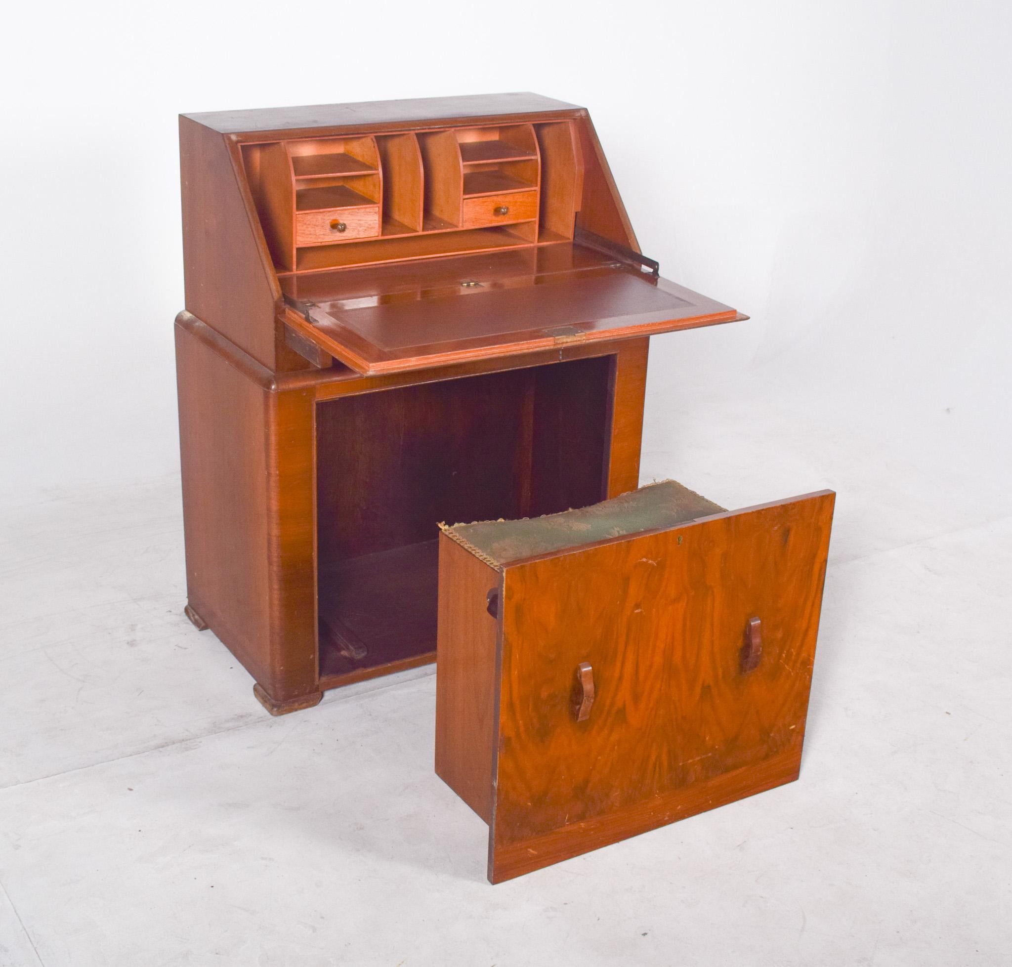 Desk with bench, in walnut. With curved lines on the sides that soften its solid structure, it has a sloping top with a flap that opens to reveal a functional interior with small niches and two internal drawers. Below, a large drawer discreetly
