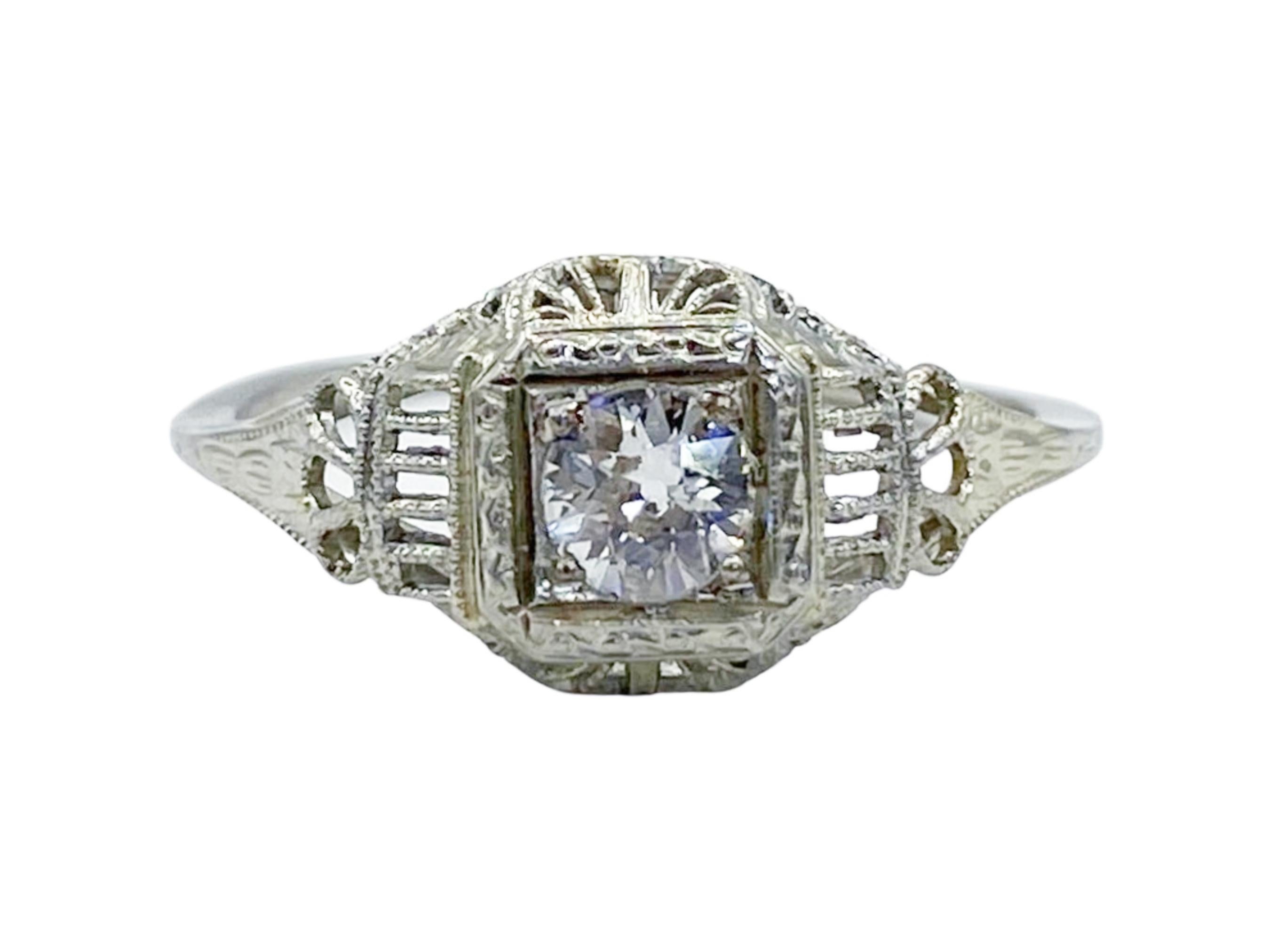 Make a statement with this one-of-a-kind antique Art Deco diamond engagement ring! Crafted in exquisite 18K white gold, this beautiful ring features a sparkling 4.5mm prong-set Old European cut diamond surrounded by filigree detailing for an