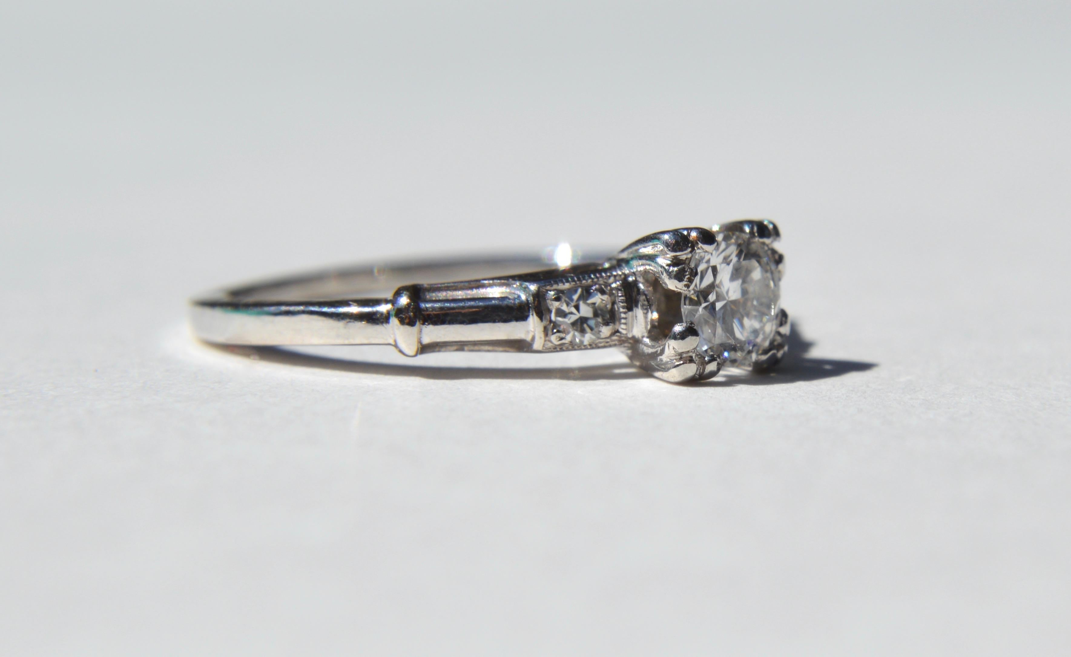 Gorgeous delicate antique Art Deco era circa 1940s platinum engagement ring with a sparkling .30 carat brilliant round cut diamond with 2 smaller diamonds. The diamonds have no inclusions seen under a loupe, and is very clear and white, have been