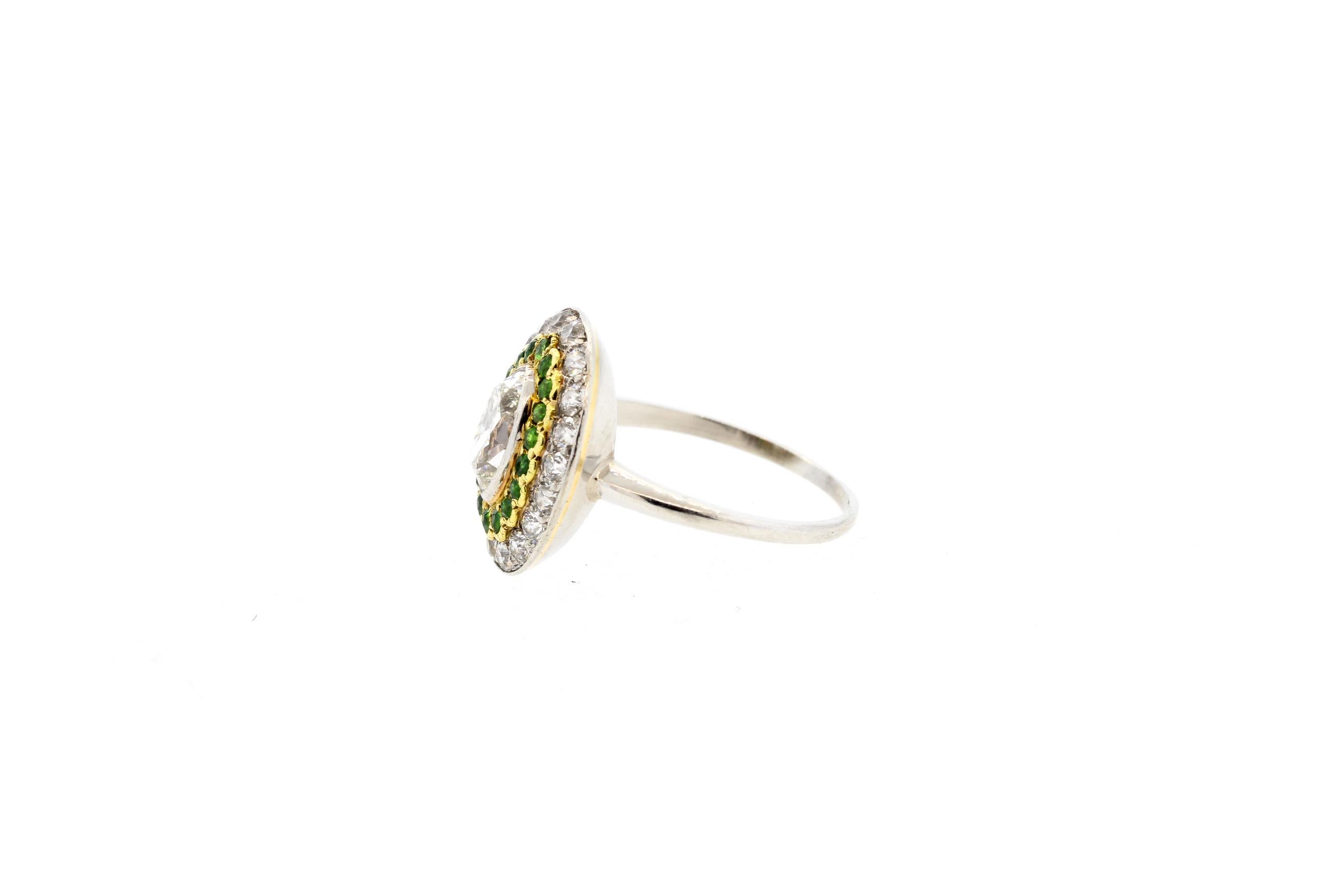 A fine antique Art Deco marquise shape diamond ring accented by demantoid garnets dating to 1920. The ring centers on an old cut marquise diamond that weighs approximately 0.95 carats and is graded as an H color and VS clarity. There are 20 round