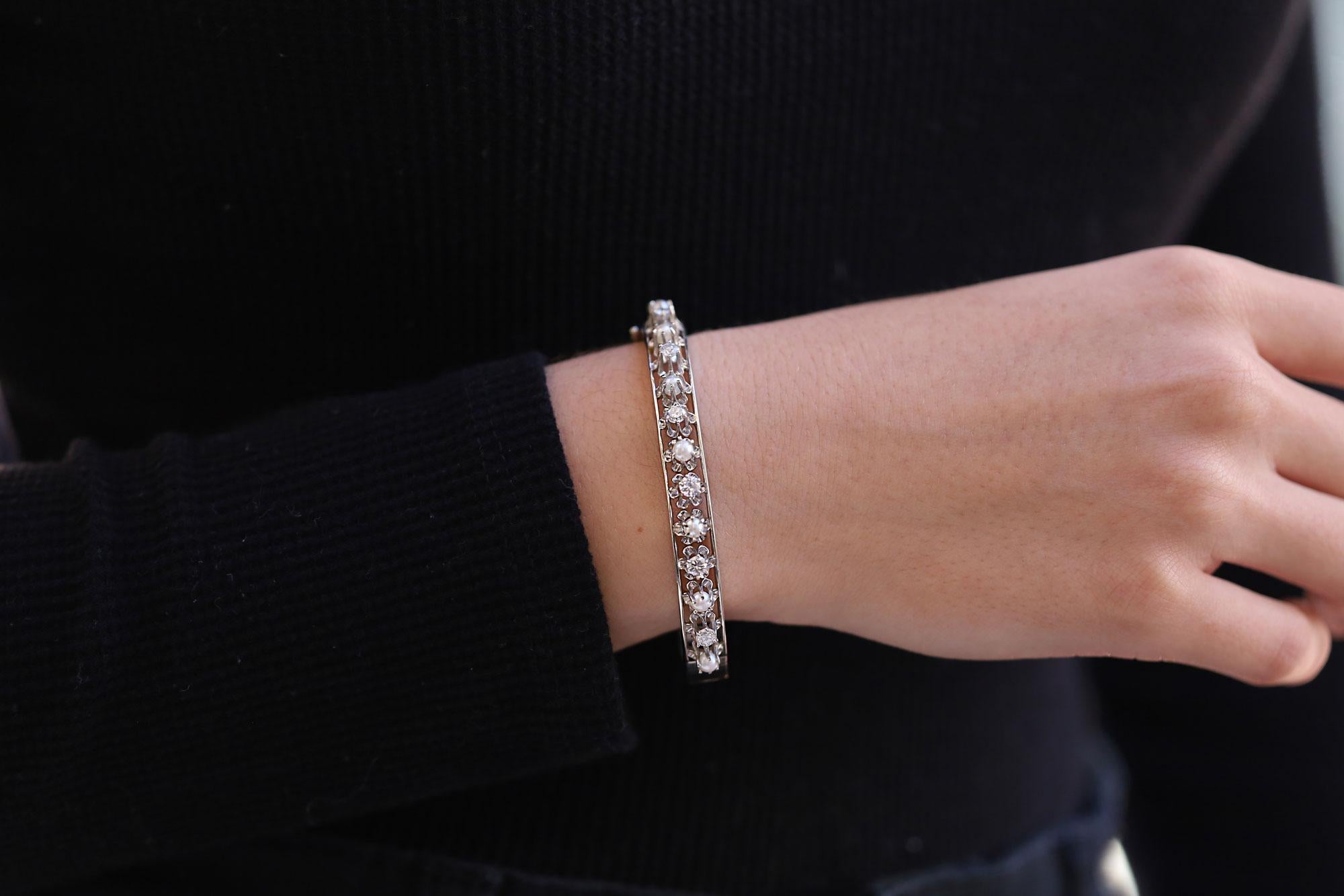 This is the perfect accessory for your wedding day jewelry and everyday. A bangle bracelet of antique distinction from the Art Deco 1920s era, this vintage estate heirloom is adorned with lustrous, cultured pearls and gleaming diamonds. The gems set