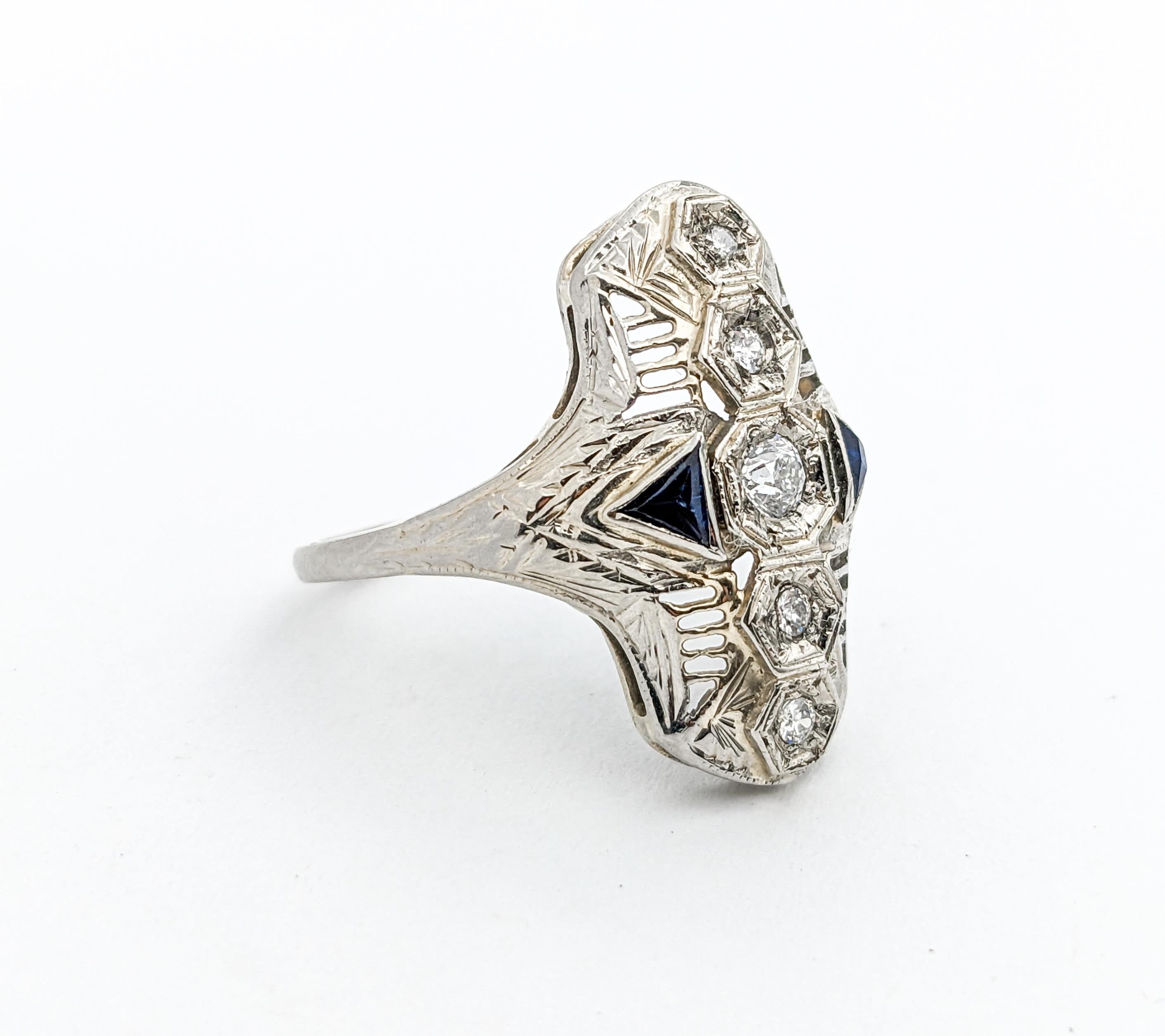 Antique Art Deco Diamond & Sapphire Filigree Shield Ring In White Gold

Introducing this stunning Art Deco diamond ring, exquisitely crafted in 18k white gold. This piece is a true testament to the timeless allure of Art Deco design, characterized