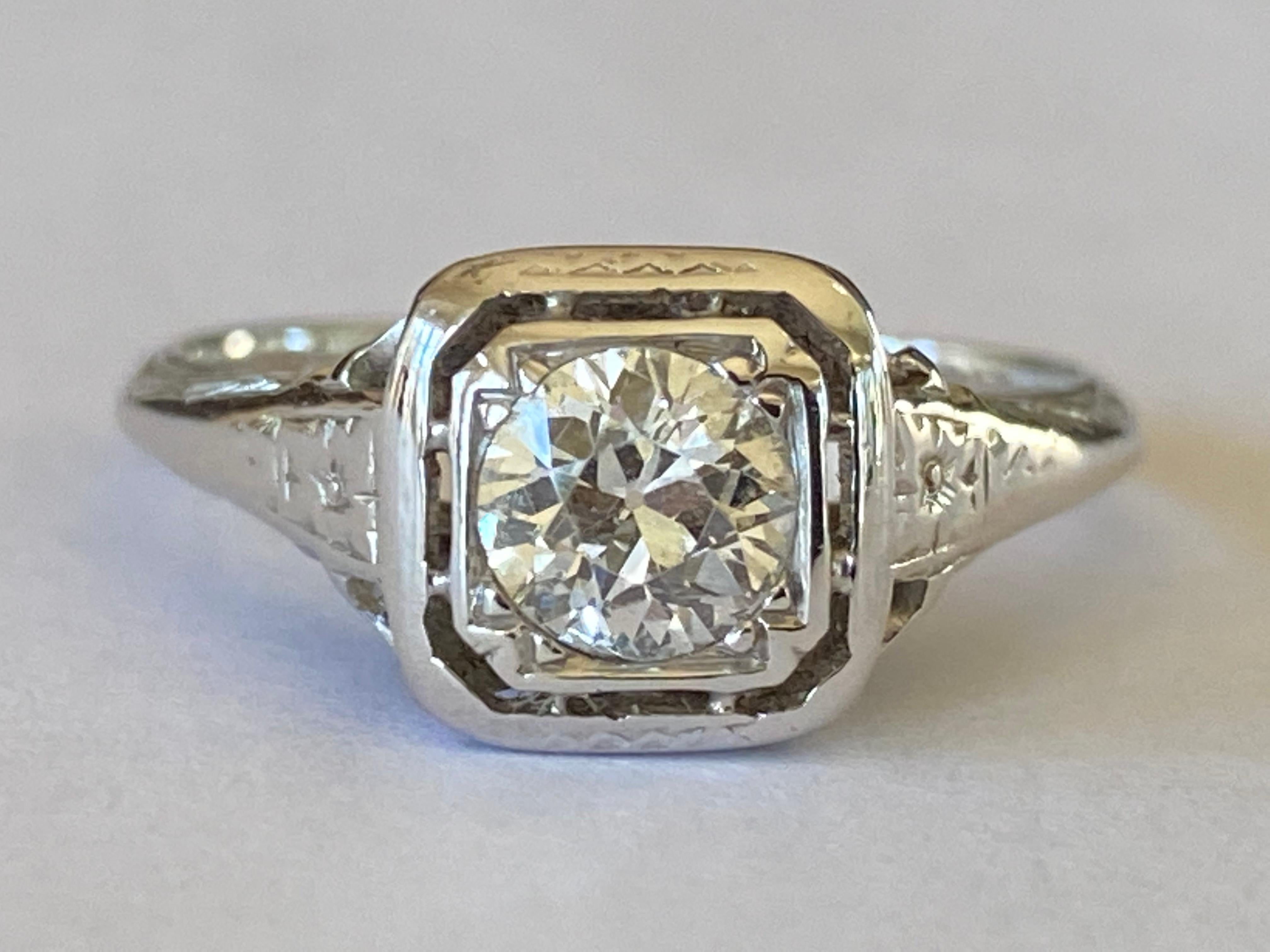 Réalisée dans les années 1920 en or blanc 18 carats, cette superbe bague Art déco est conçue autour d'une pierre centrale en diamant de taille Vieille Europe d'environ 0,55 carats, de couleur I-J et de pureté VS, et d'un délicat motif filigrane. 
