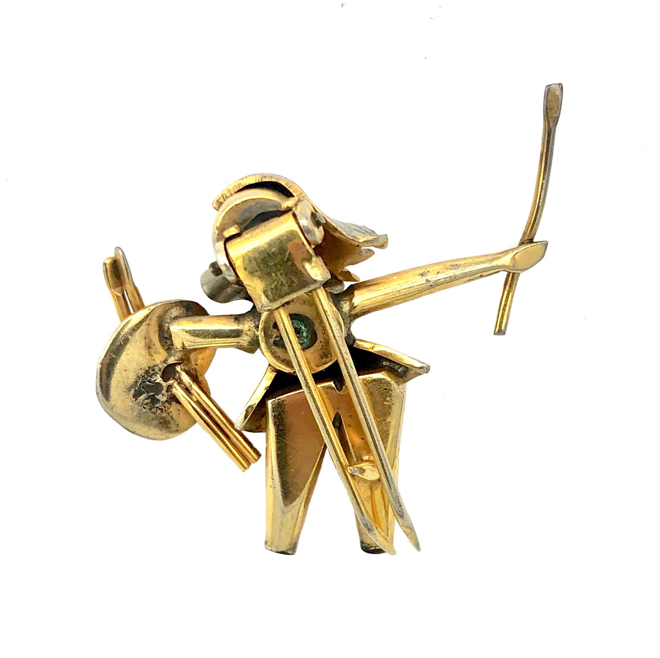 This charming Art Deco dress clip of a lady painter proudly holding a brush in her right hand and palette and more brushes in her left hand has been made in 1930 ca out of gilt metal. She wears a short dress and a large ribbon tied to a bow around
