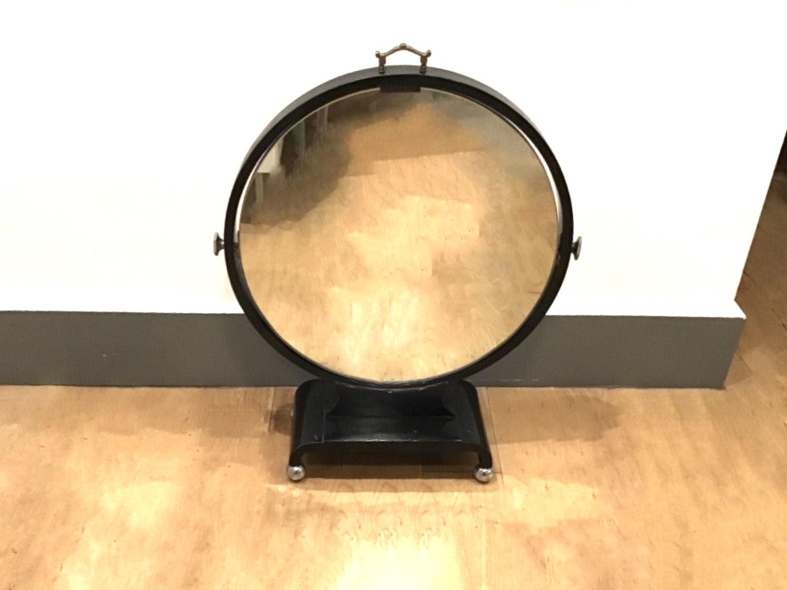 A charming rare large antique Art Deco ebonised wooden round table top mirror set on round chrome ball shaped feet .The mirror tilts and is secured by two side bolting hexagonal steel handles and also has a strong brass handle on the top. The Glass