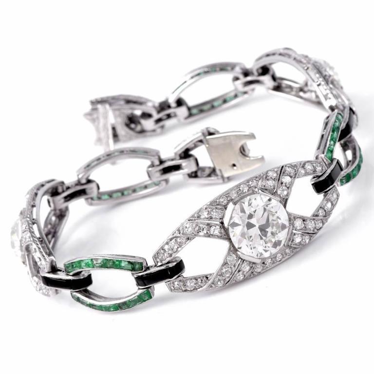 This antique Art Deco link bracelet of immaculate design and craftsmanship is constructed in solid platinum. It is composed of gracefully convex diamond and emerald links adjoined by delicate links set with an onyx top. 
It is set with three large