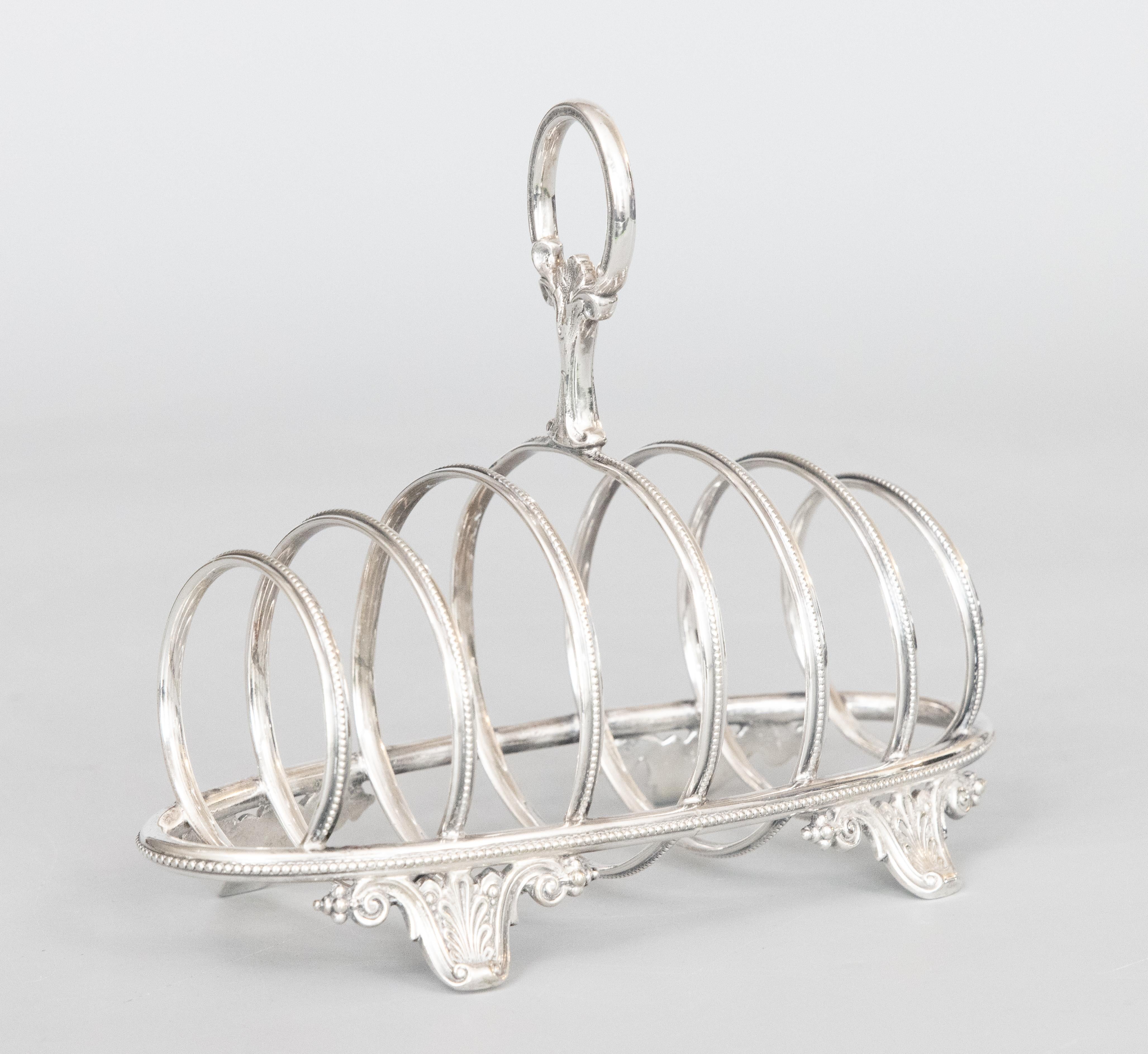 A fine Art Deco English silverplate six slot toast rack, circa 1900. No maker's mark. This stunning toast rack has a sleek and stylish barrel shaped geometric design, beaded trim, and ornate acanthus leaf feet and finial. It's perfect for serving