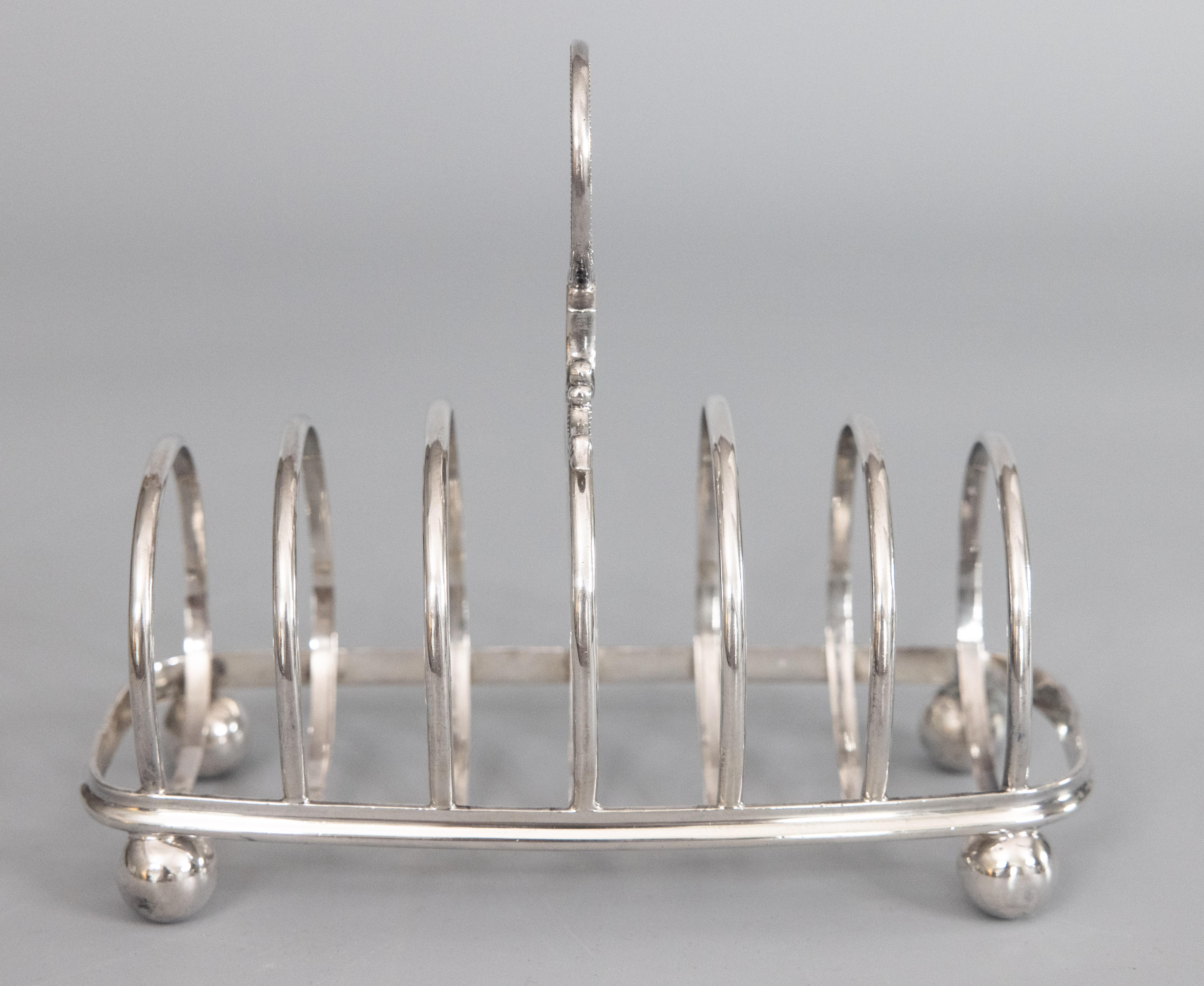 A fine antique English Art Deco silverplate six slot toast rack. Hallmarks on rim. This stunning toast rack has a sleek and stylish barrel shaped geometric design, beaded finial, and charming ball feet. It's a nice large size, perfect for serving