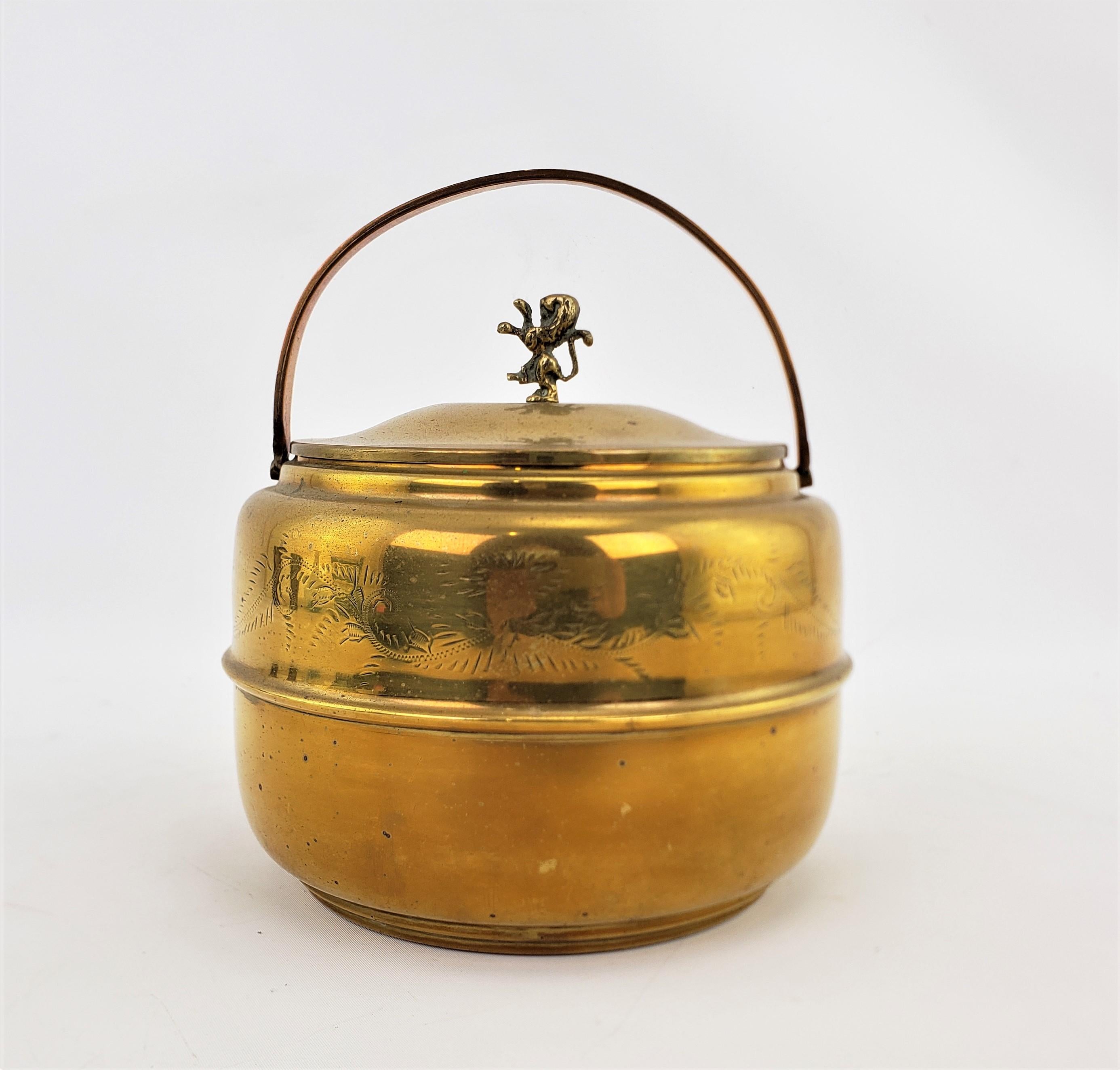 This brass ice bucket shows no maker's signature, but is presumed to have originated from England and dating to approximately 1920 and done in the period Art Deco style. The outer shell and handle are composed of solid brass with some accenting